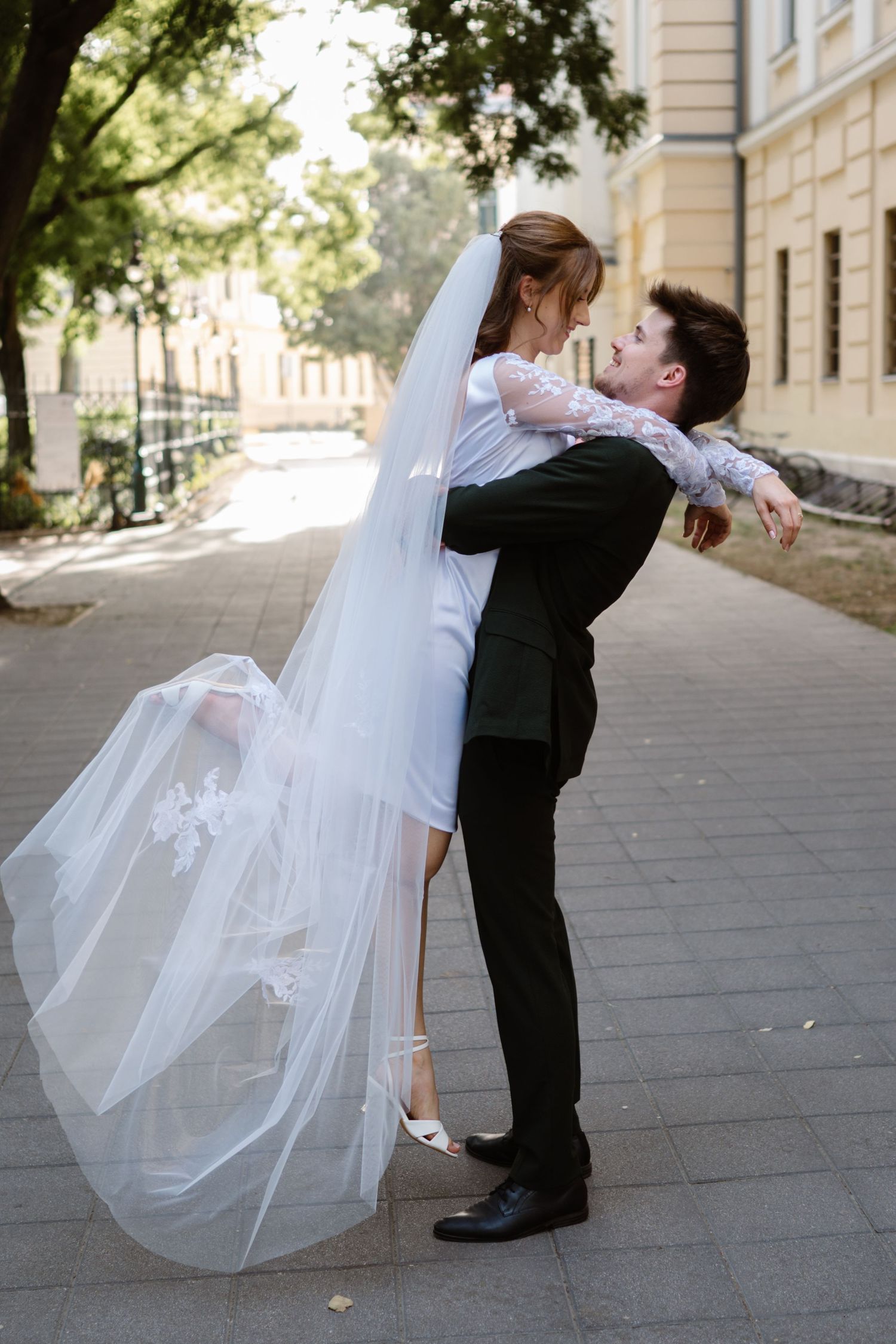 Romantic wedding dance dip pose on a stone pathway with flowing white veil.