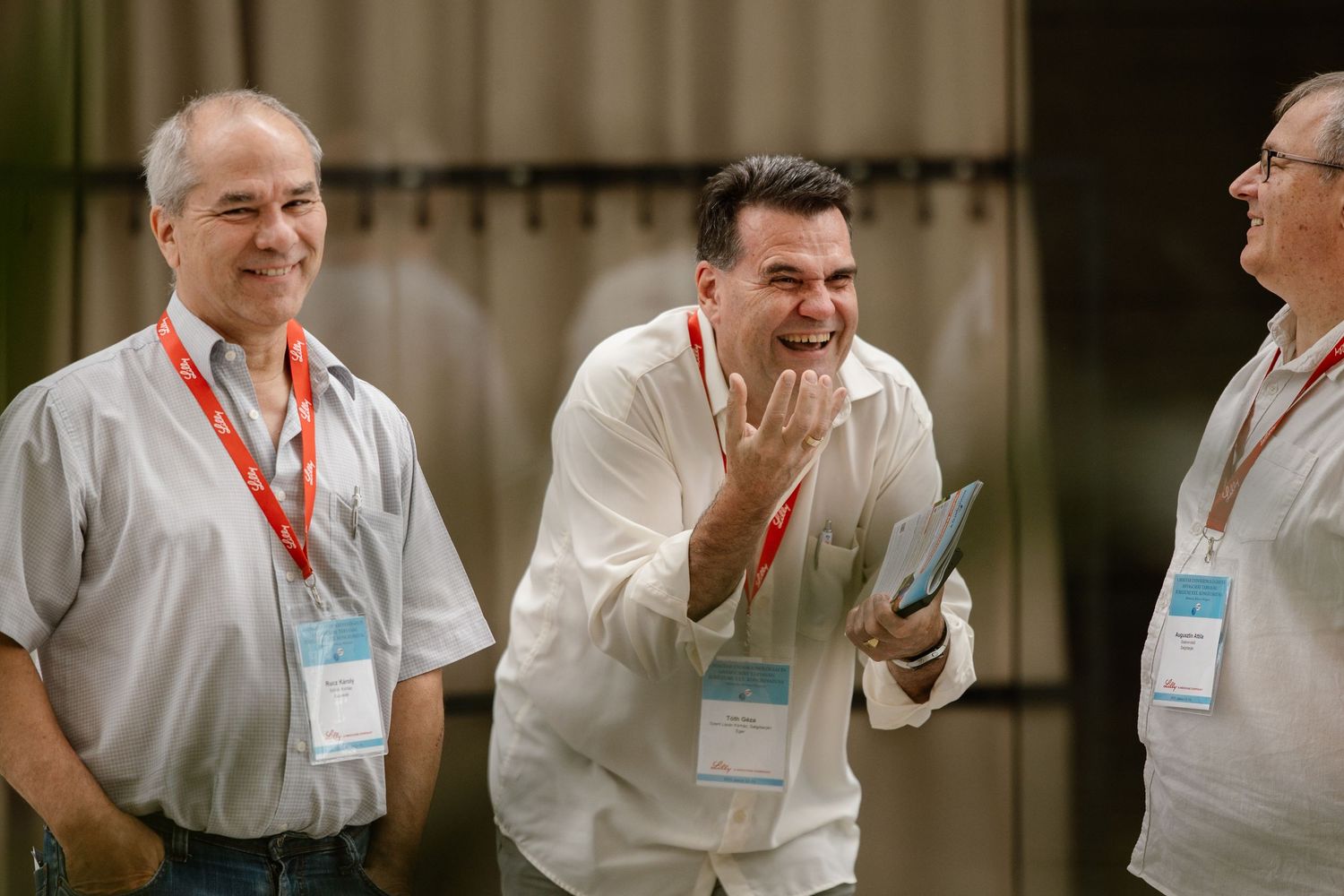 A group of people in white shirts and name tags share a laugh during a conference or meeting.