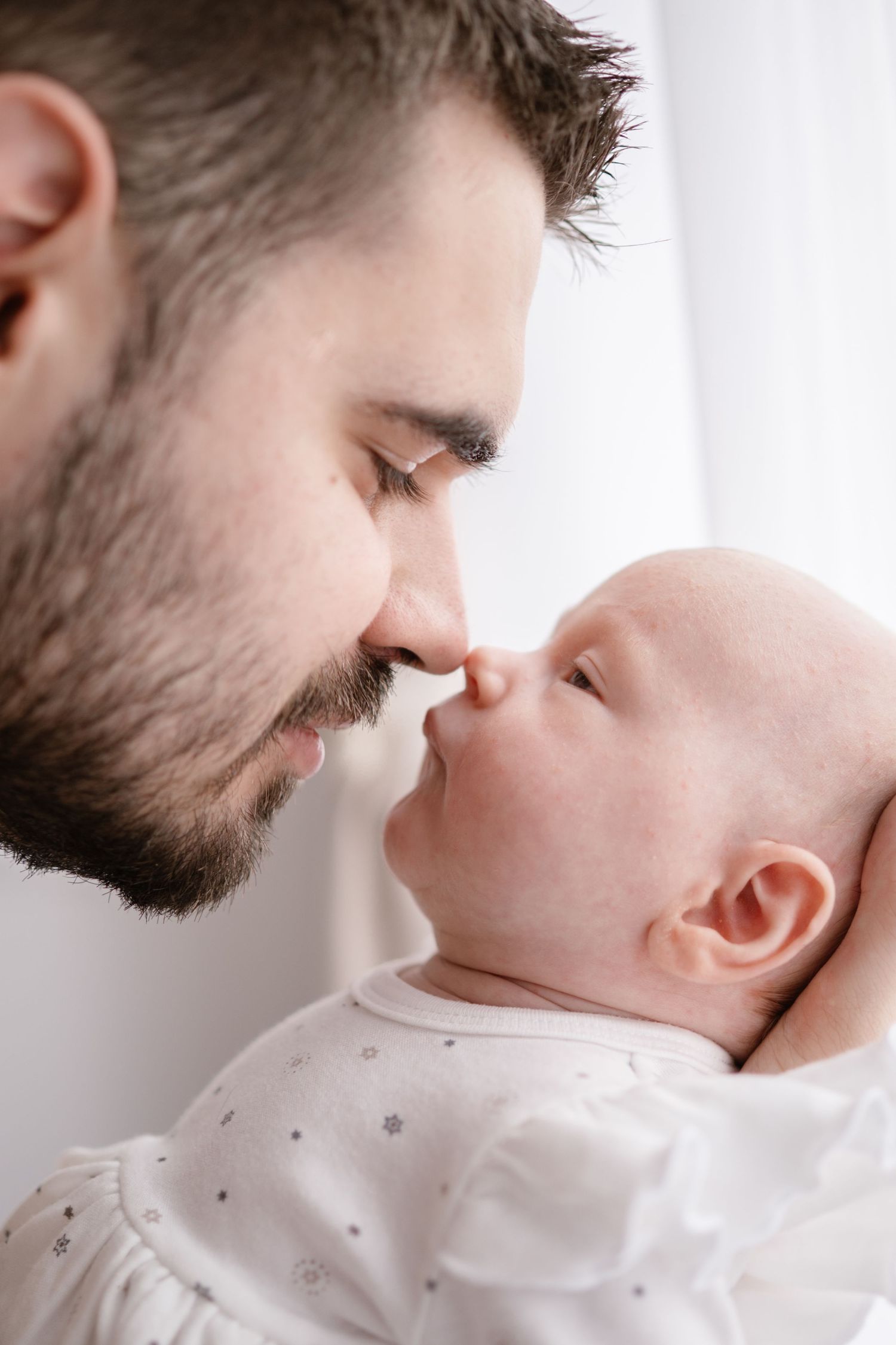 A tender moment captured in a series of close-up shots showing affectionate interaction with a baby in white clothing.