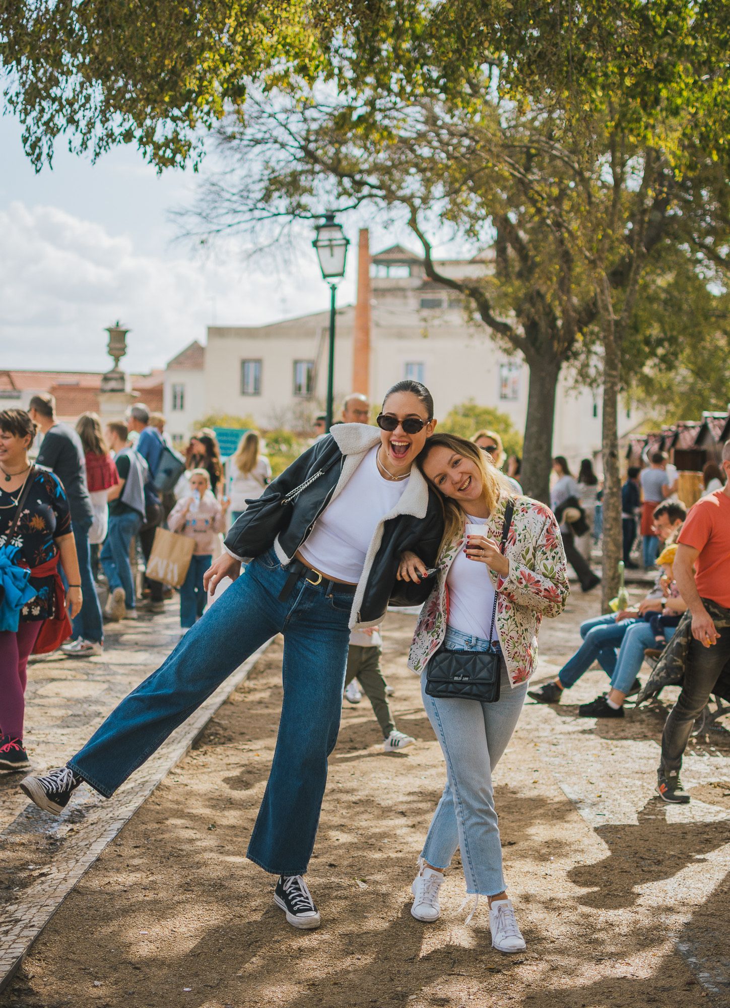Friends enjoying a sunny day in a lively park or plaza setting.