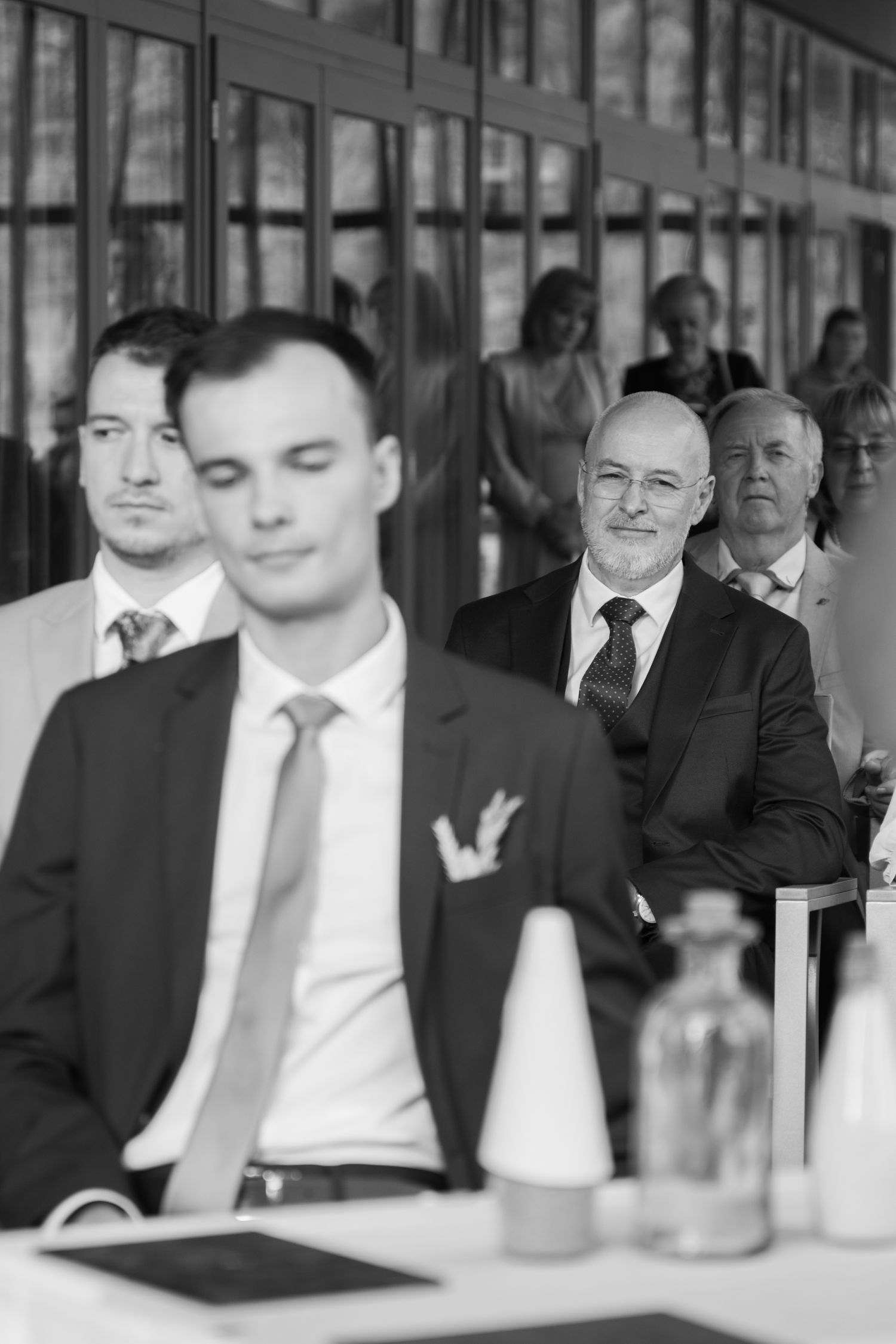 Black and white photo of wedding guests seated during an indoor ceremony.