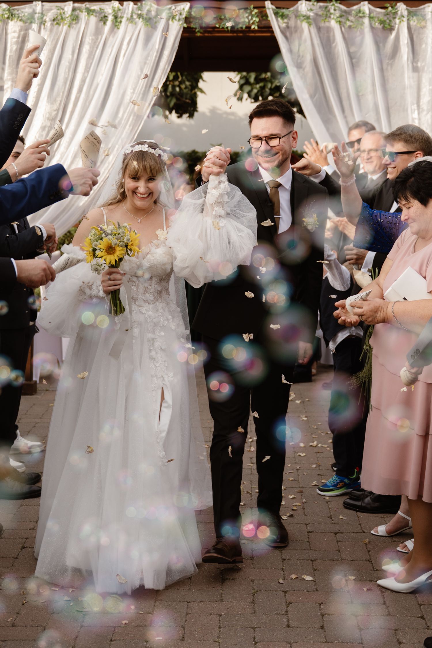 Wedding guests blow bubbles during an outdoor celebration ceremony.