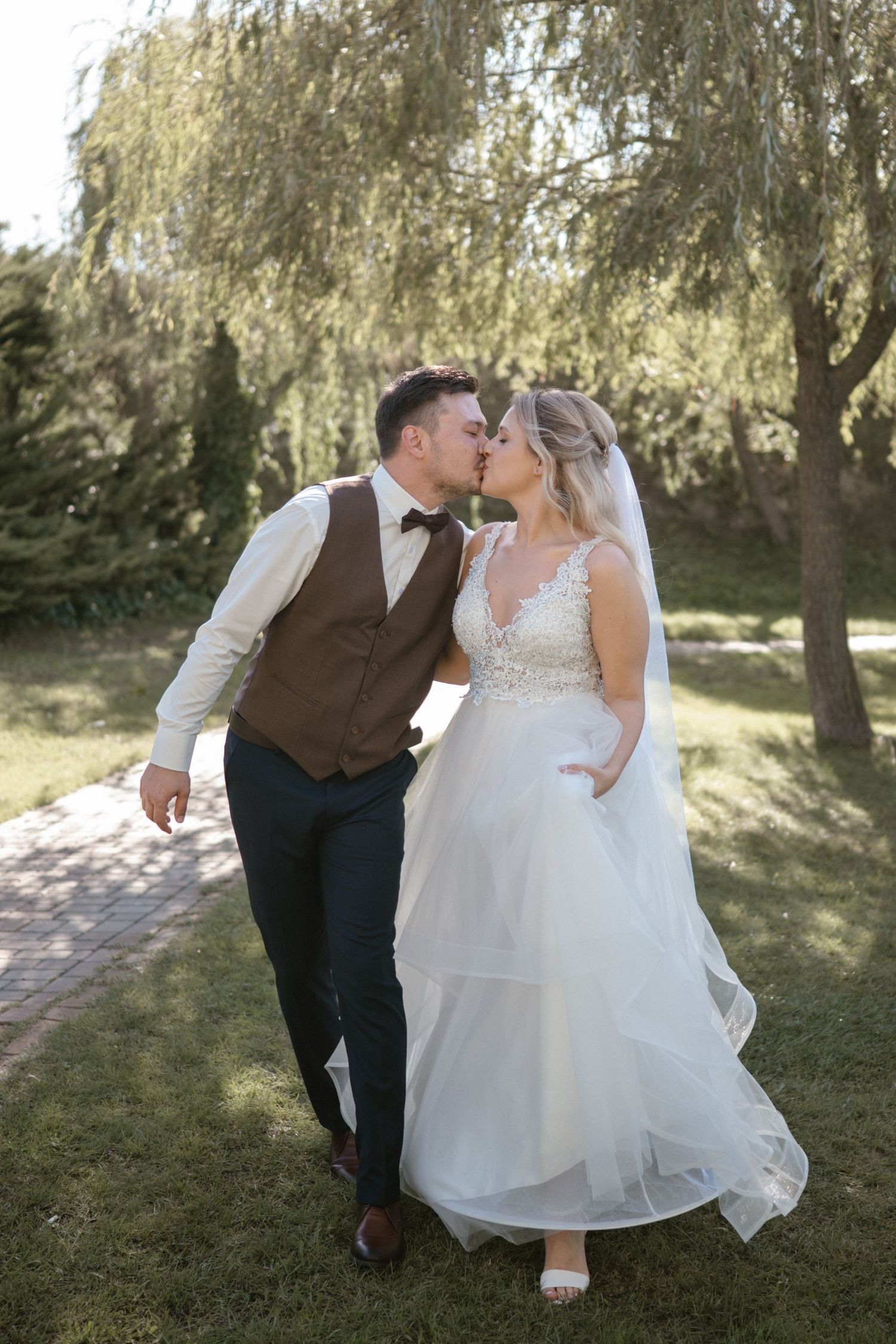 Newlyweds share intimate moments on their wedding day under willow trees.