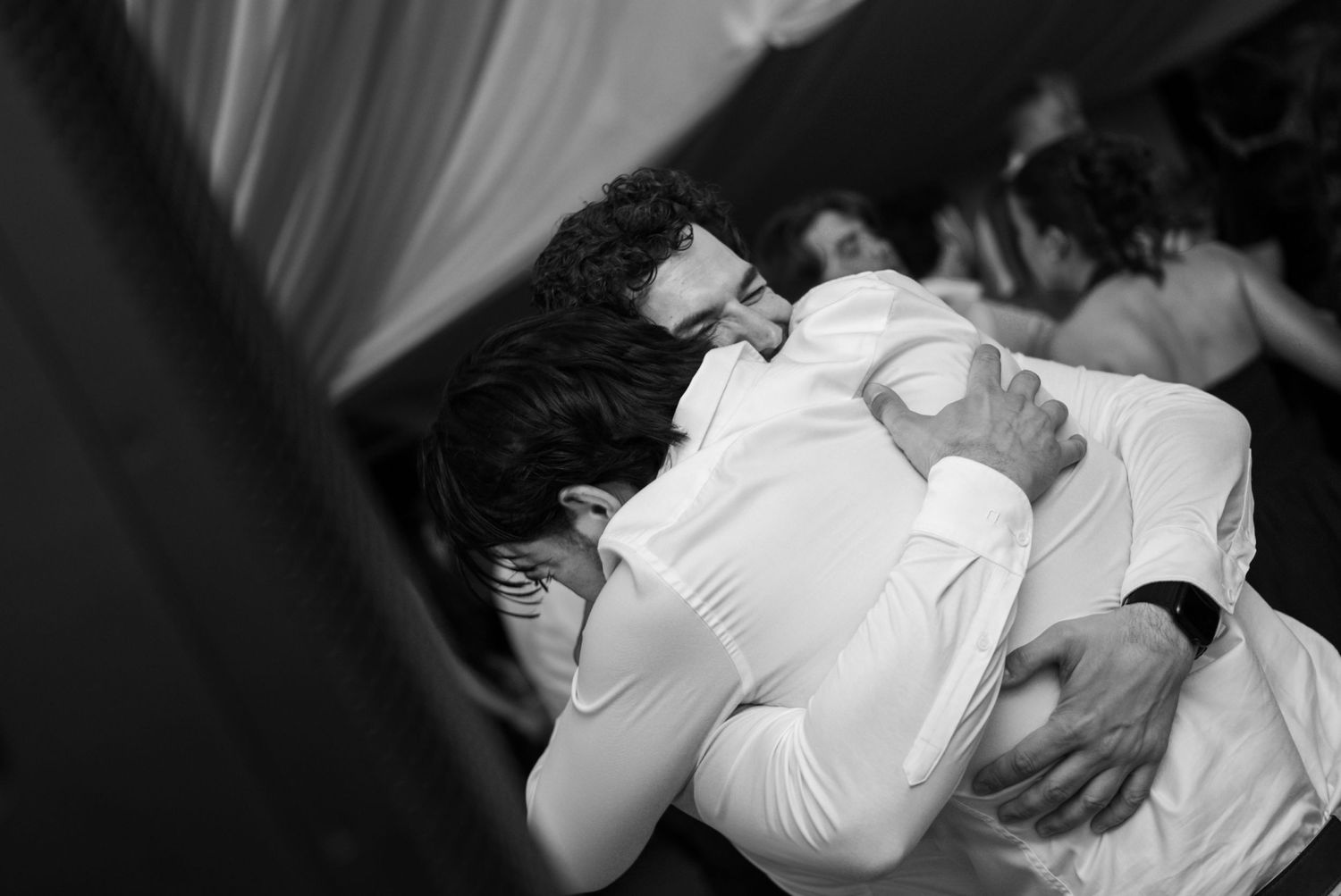Two people sharing an emotional embrace on a dance floor in a black and white wedding photo.