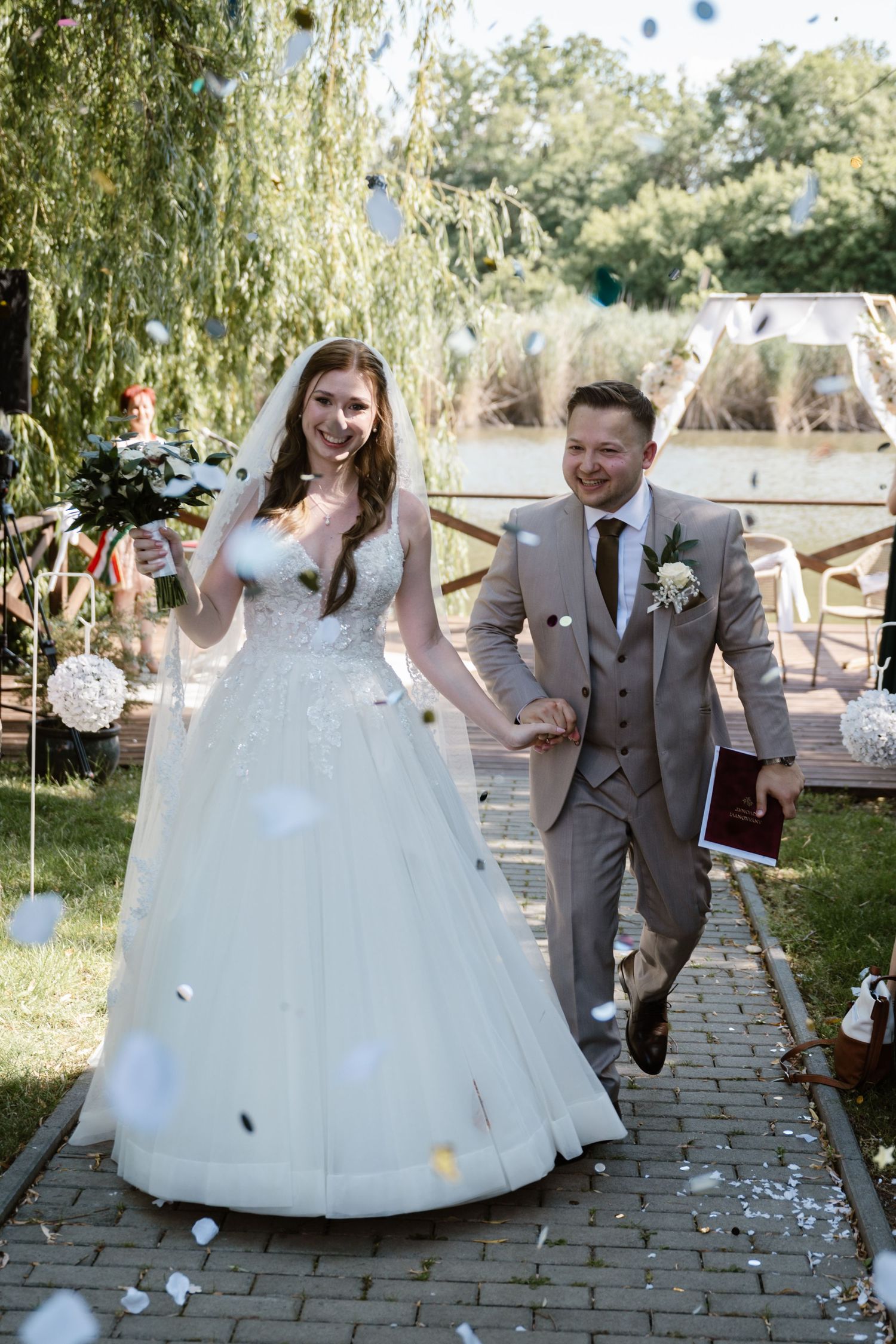Newlyweds celebrating and walking down the aisle with confetti falling around them.