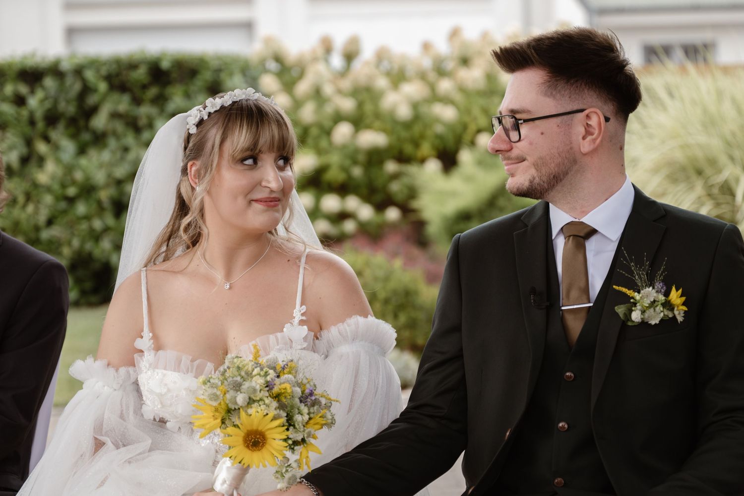 Wedding couple sharing intimate moments with sunflowers and white floral bouquet.