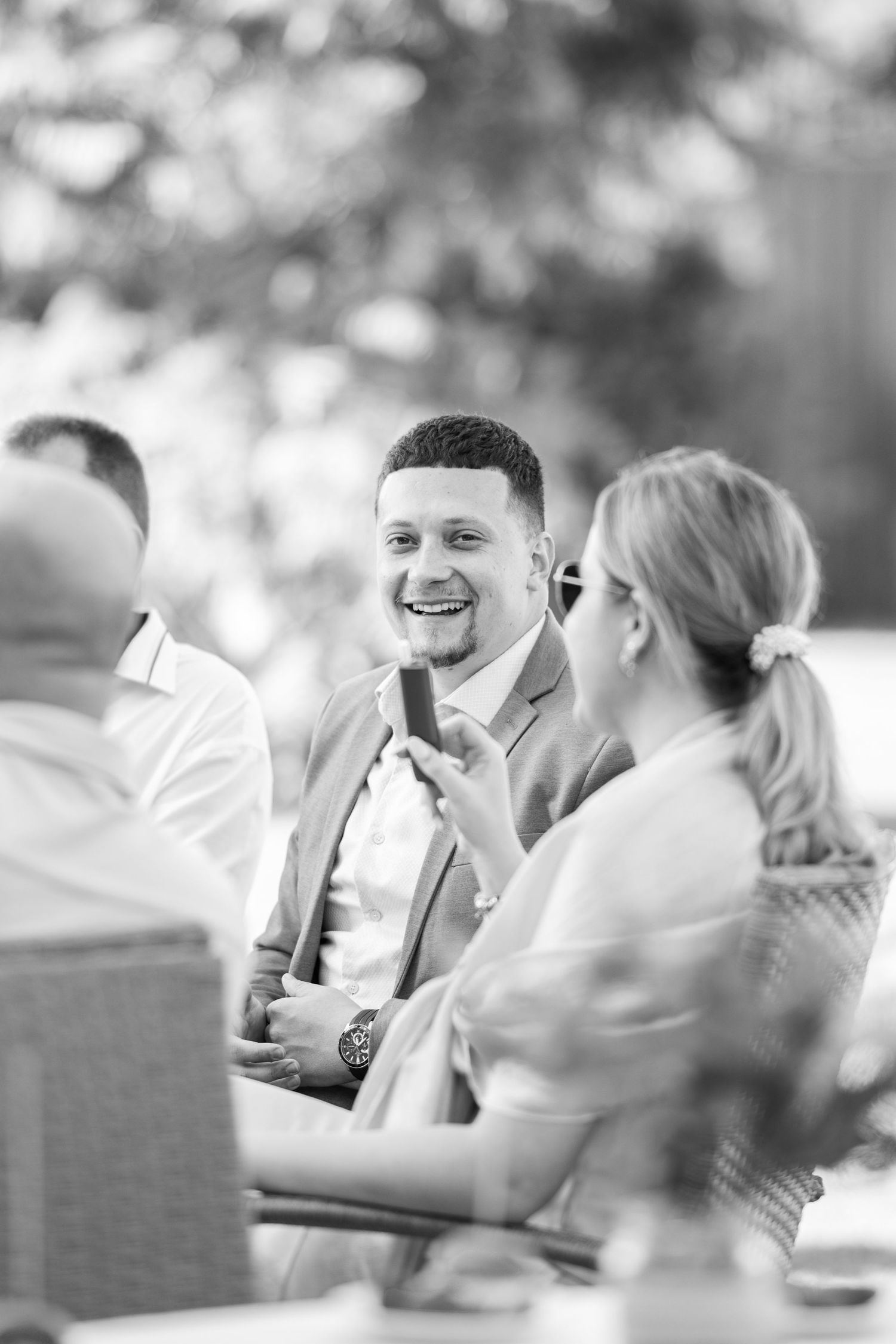 Black and white candid of wedding guests laughing at reception.