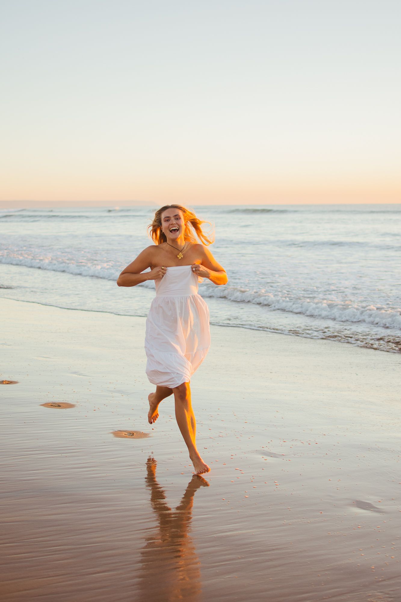 Carefree moments of someone running and playing along the shoreline at sunset.