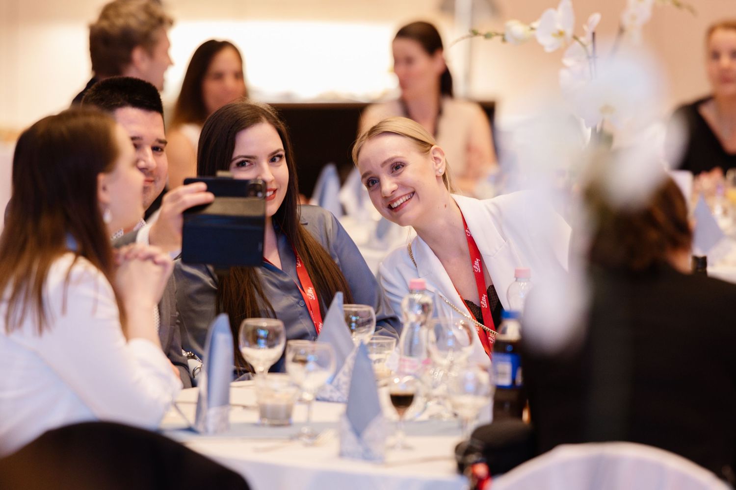 Group enjoying conversation around dining table at formal event with wine glasses.