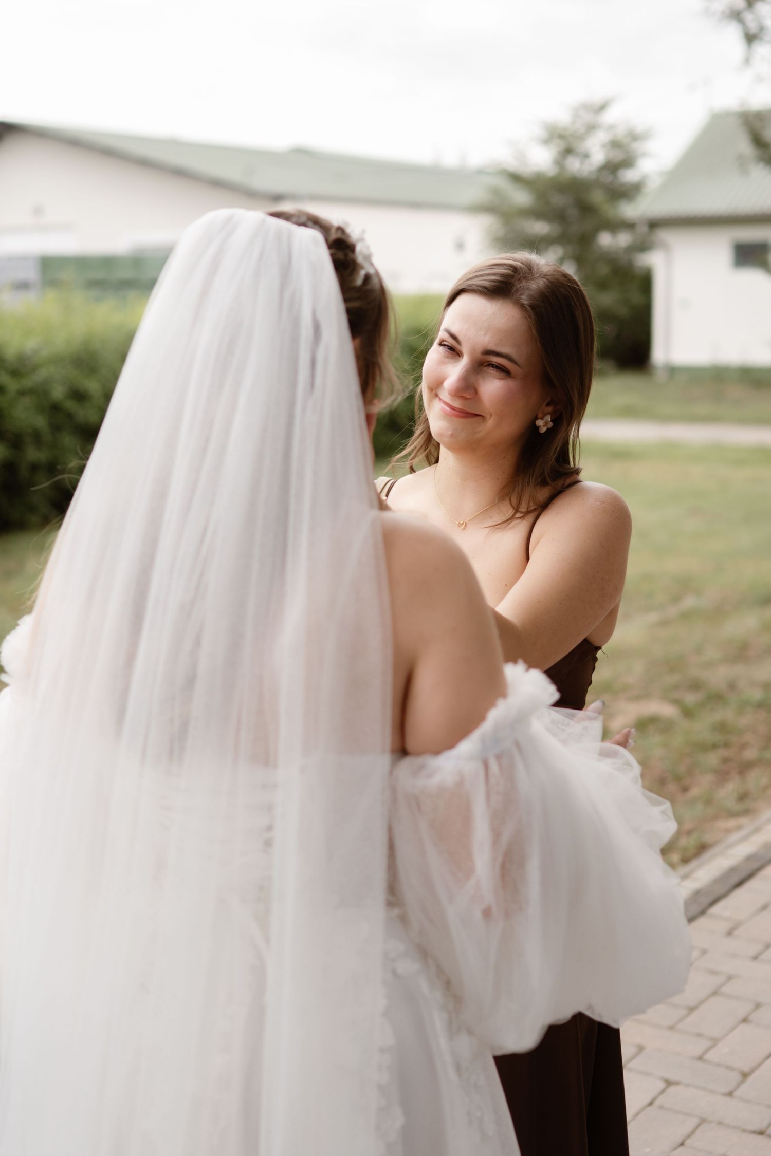 An intimate moment captured between two people at a wedding, with a flowing white veil visible.