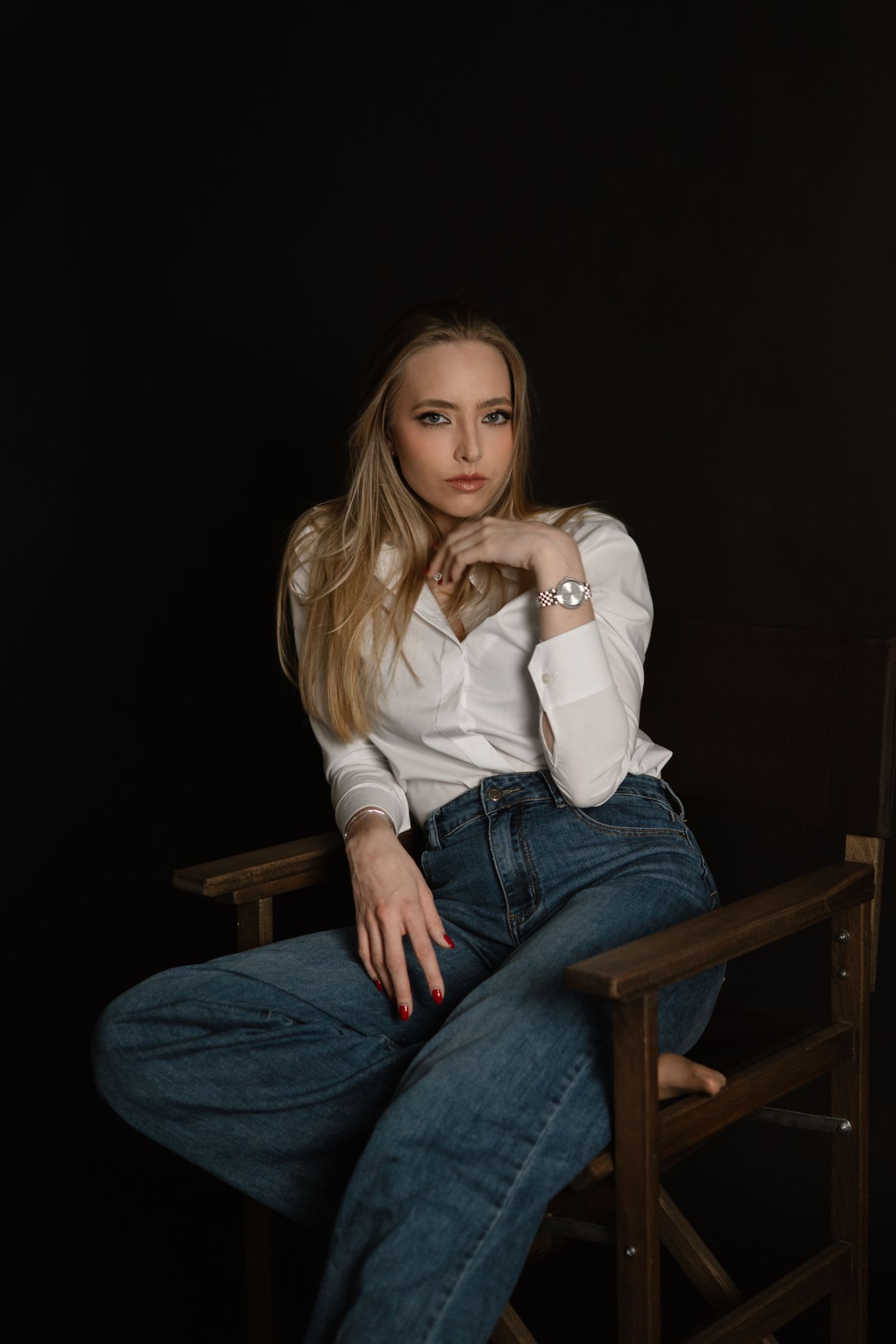 Moody studio portraits in casual attire against dark background with wooden bench.