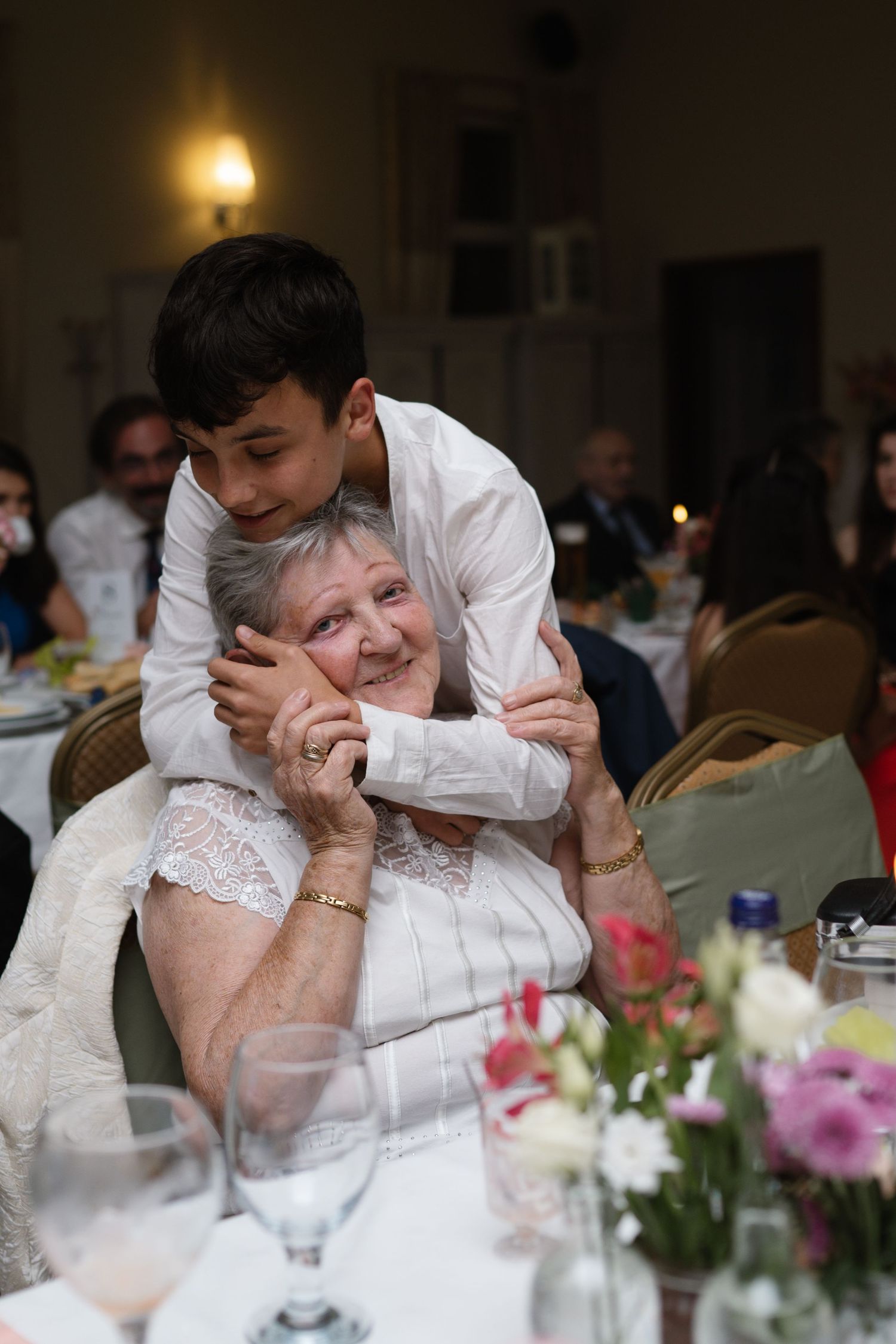 Candid moment at a wedding reception with floral centerpieces and warm lighting.