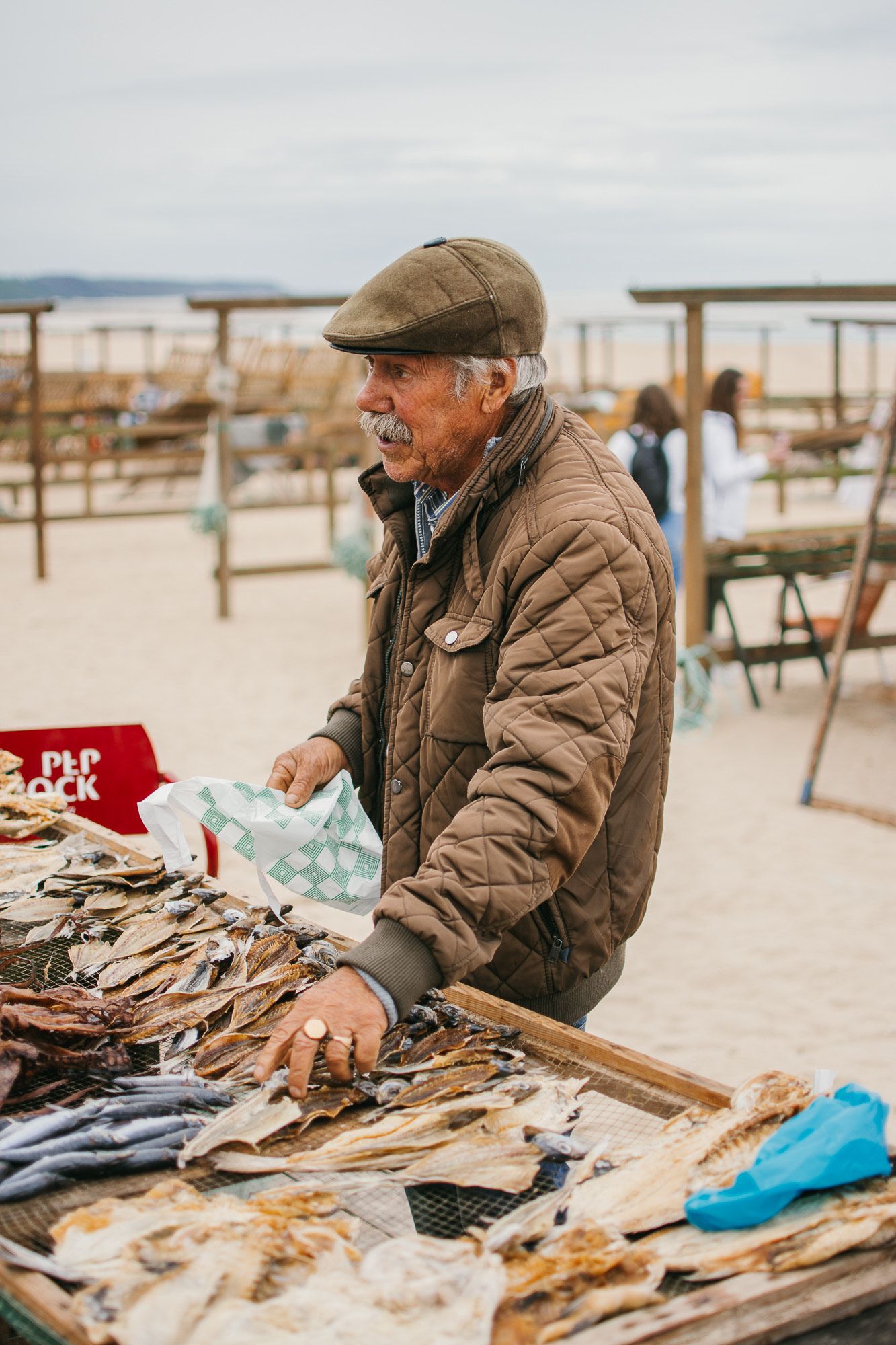 Vendor displaying handmade crafts and wares at a beachside market.
