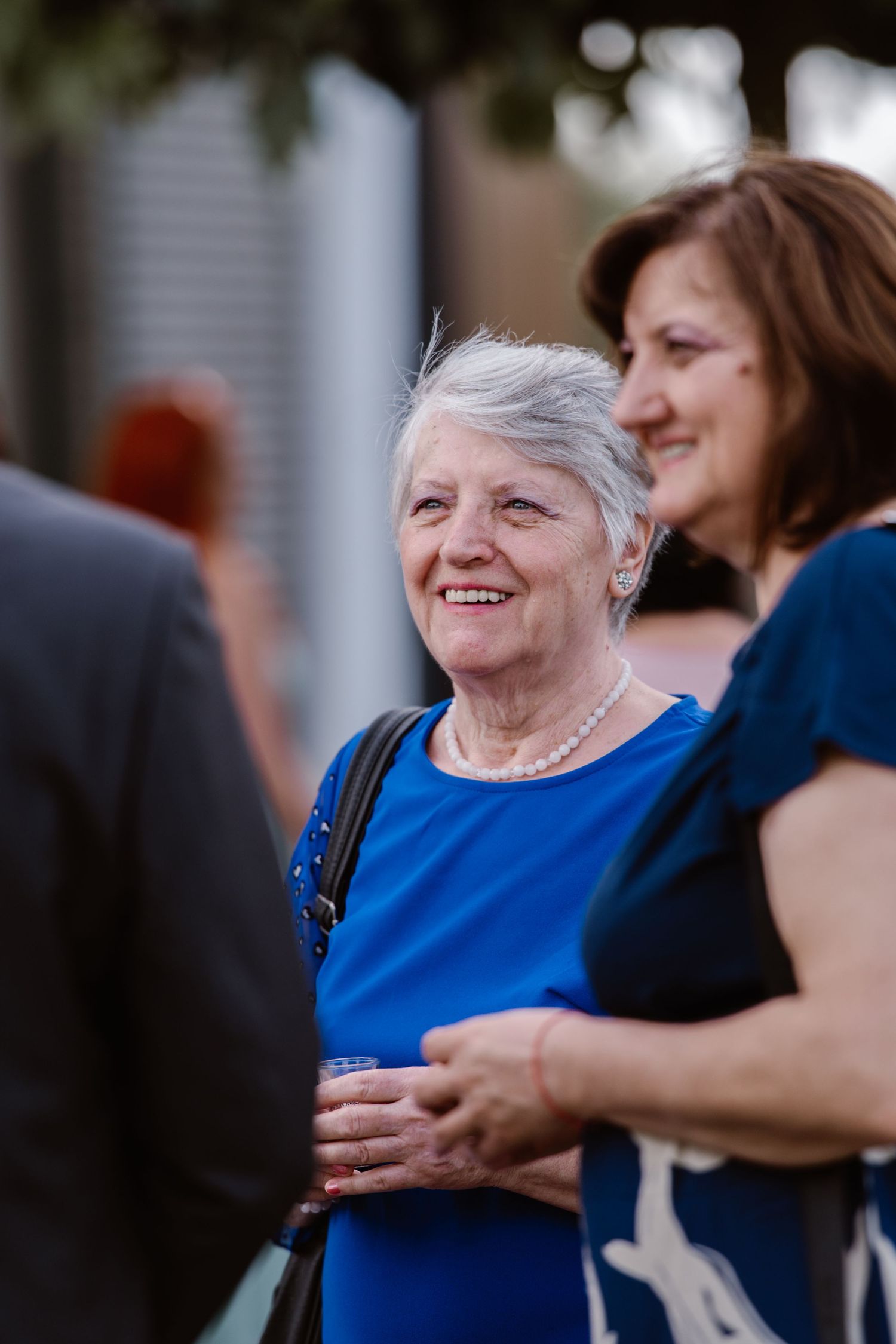 Two women in blue attire sharing a joyful moment at an outdoor event.