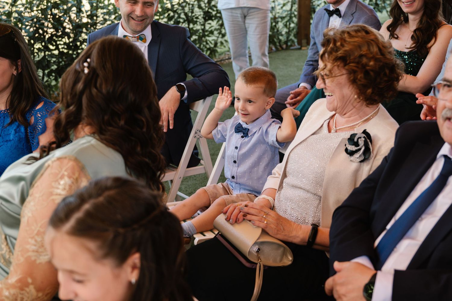 Couple seated during outdoor garden wedding ceremony with floral decorations.