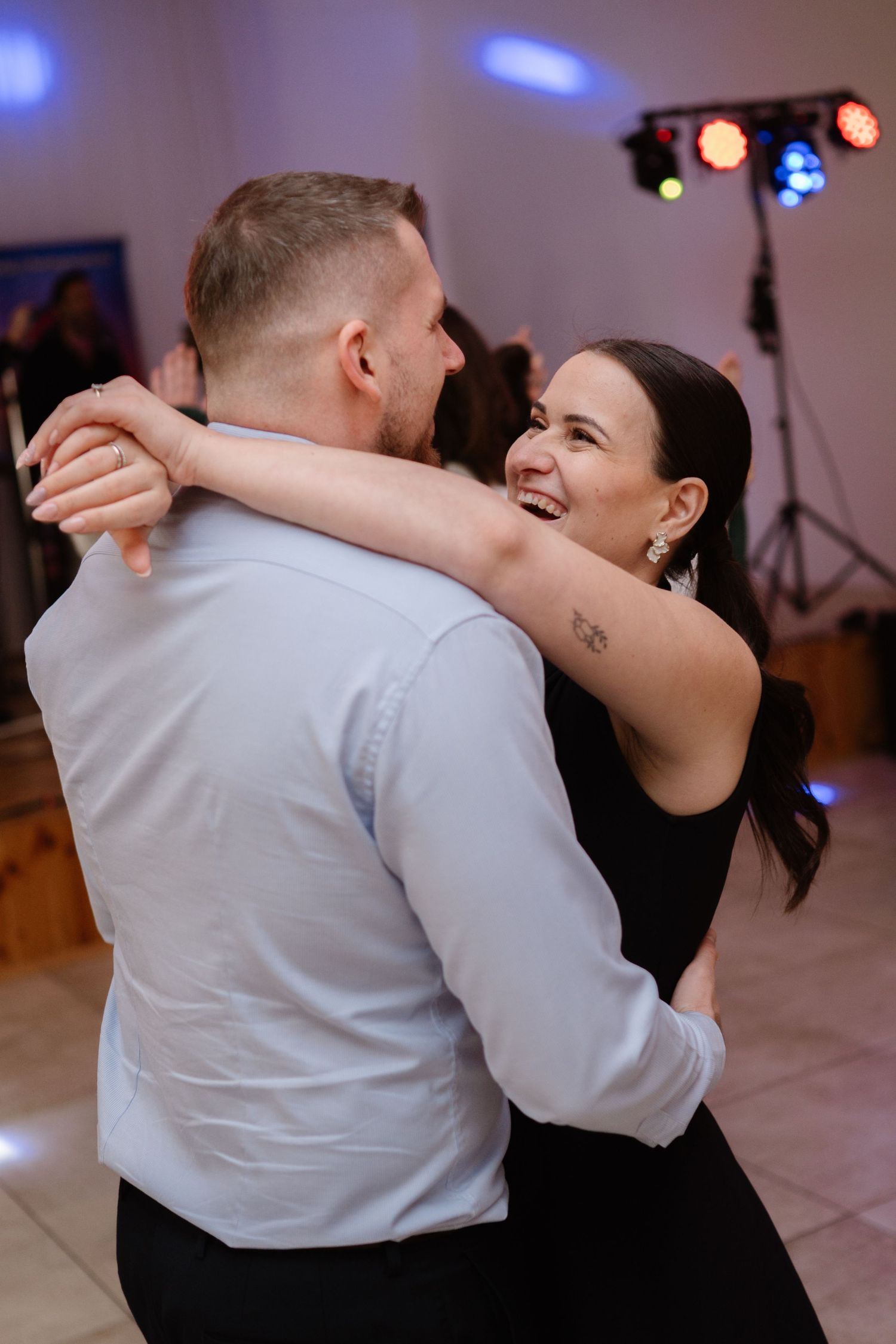 Couples dancing together under blue and purple lighting at an indoor event.