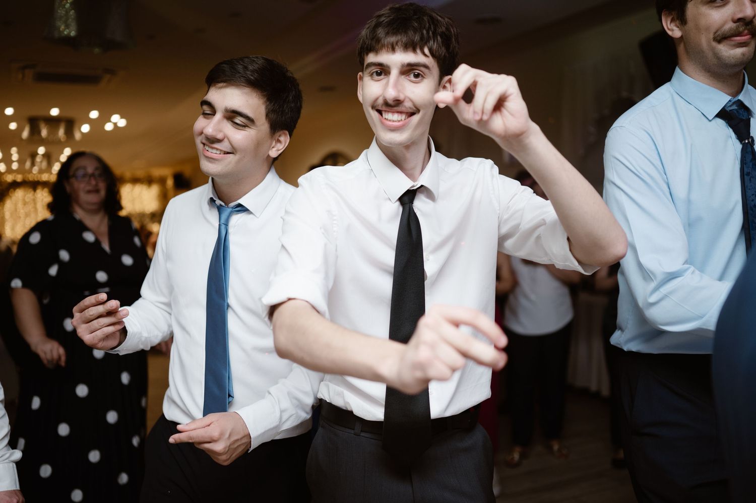 Wedding guests dance and celebrate together at an indoor reception venue.