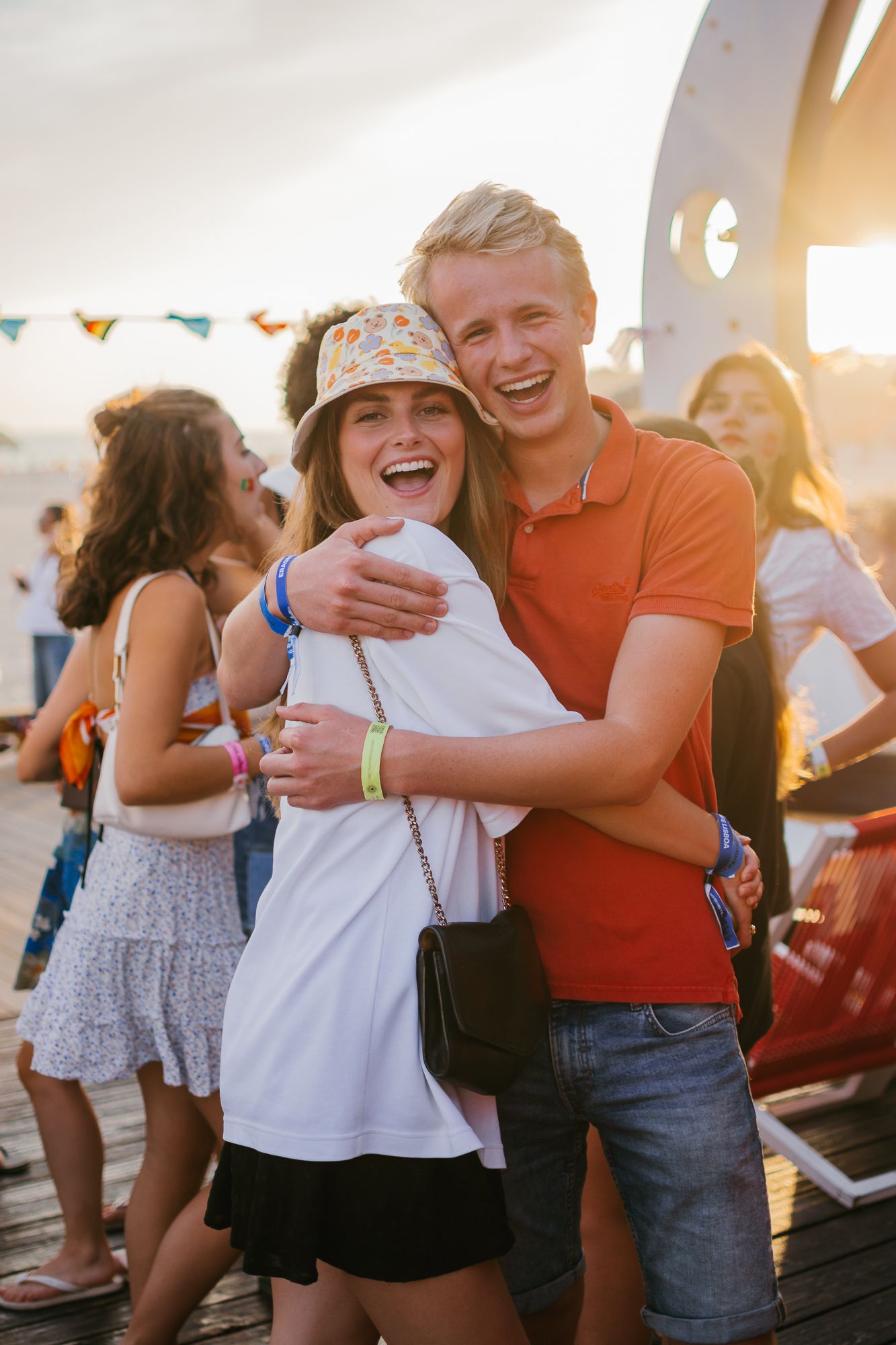 Friends sharing joyful hugs and laughter at a sunset gathering.