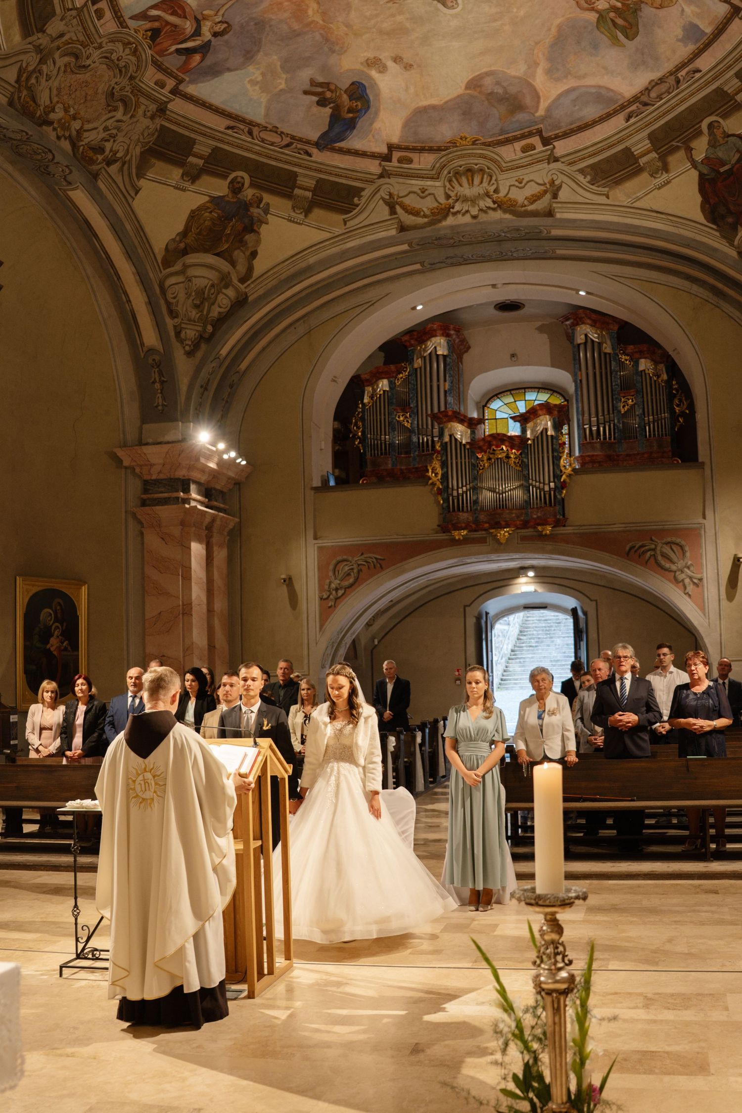 Wedding ceremony in a grand church with baroque architecture and painted ceiling.
