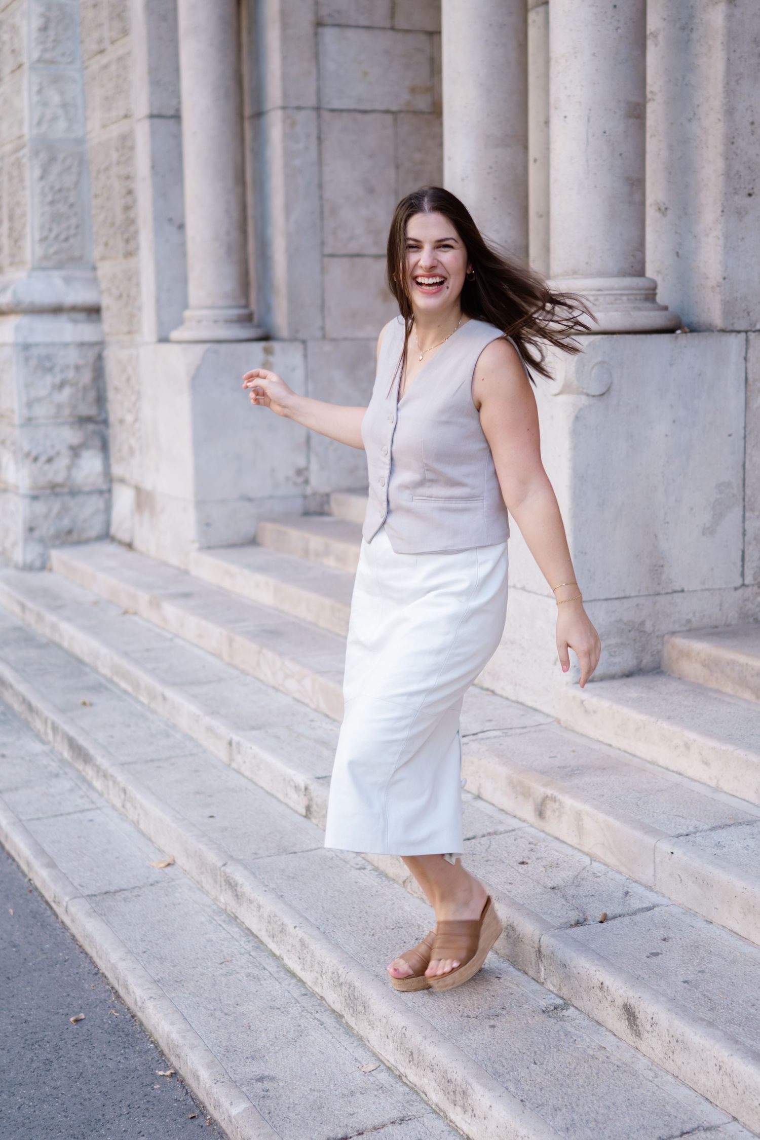 Woman in white dress walking down stone steps with columns in a sequence of movement shots.
