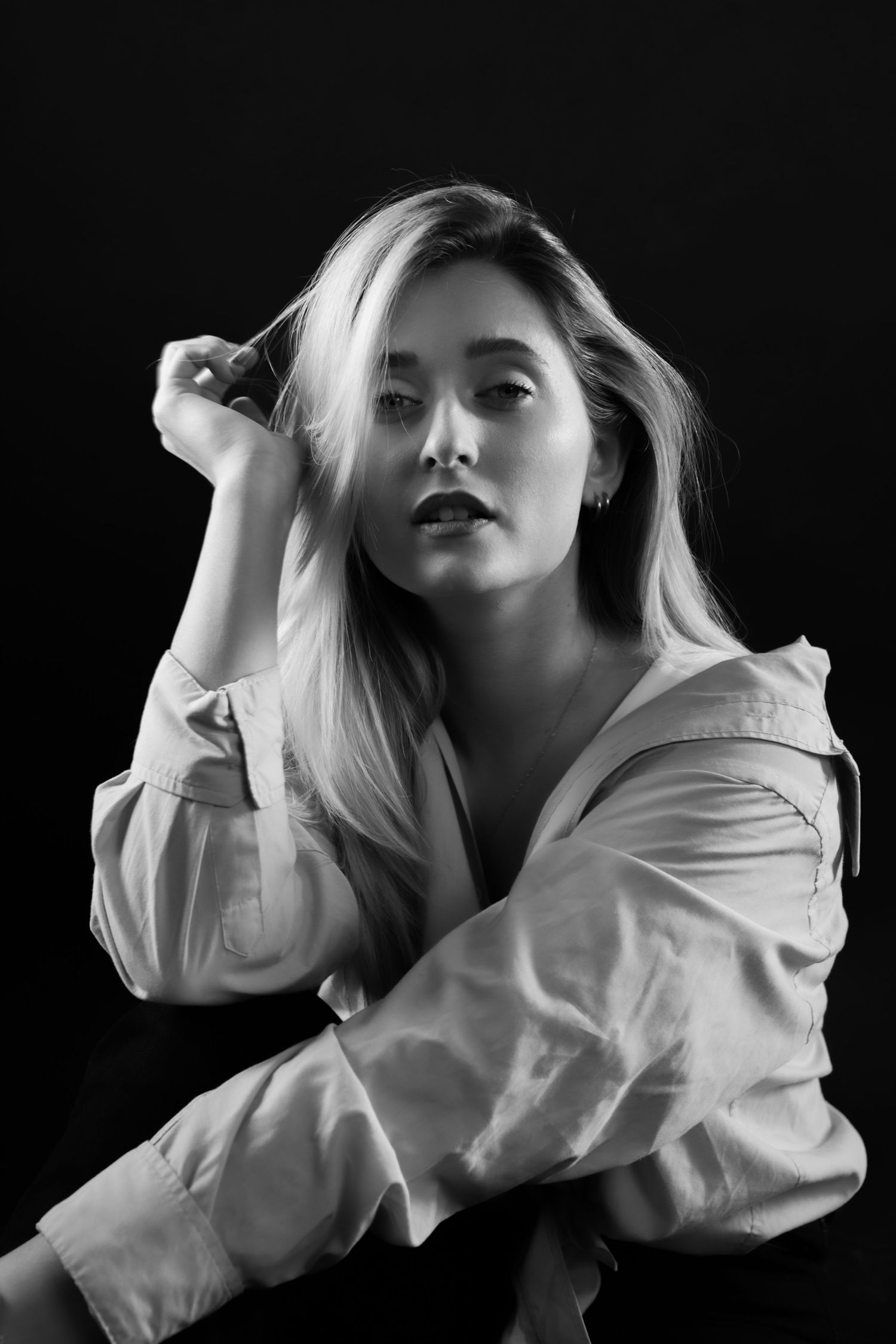 Dramatic black and white studio portraits featuring flowing white shirt against dark background.