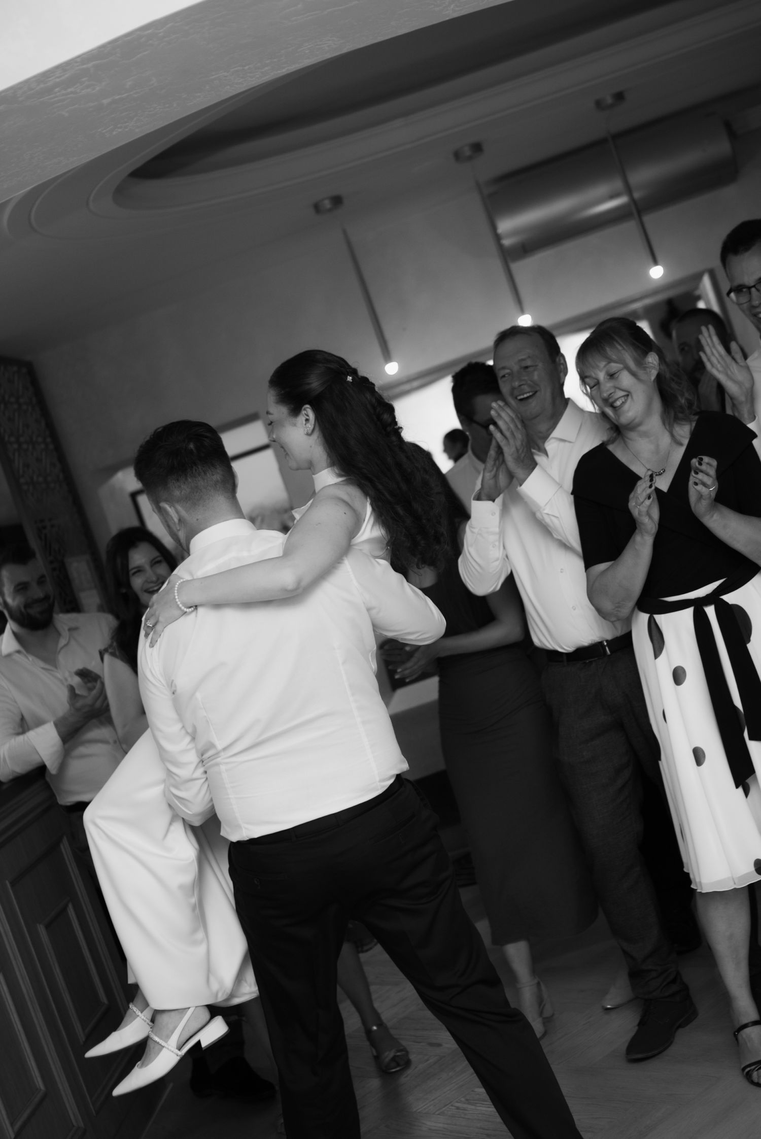 Black and white photo of wedding guests dancing joyfully together on the dance floor at a lively reception.