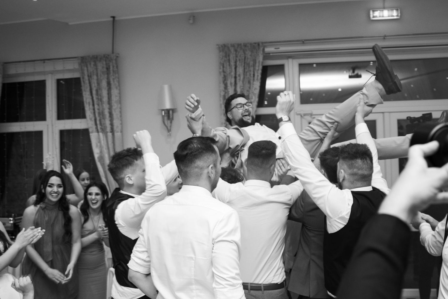Wedding guests dancing and celebrating together at an indoor reception venue.