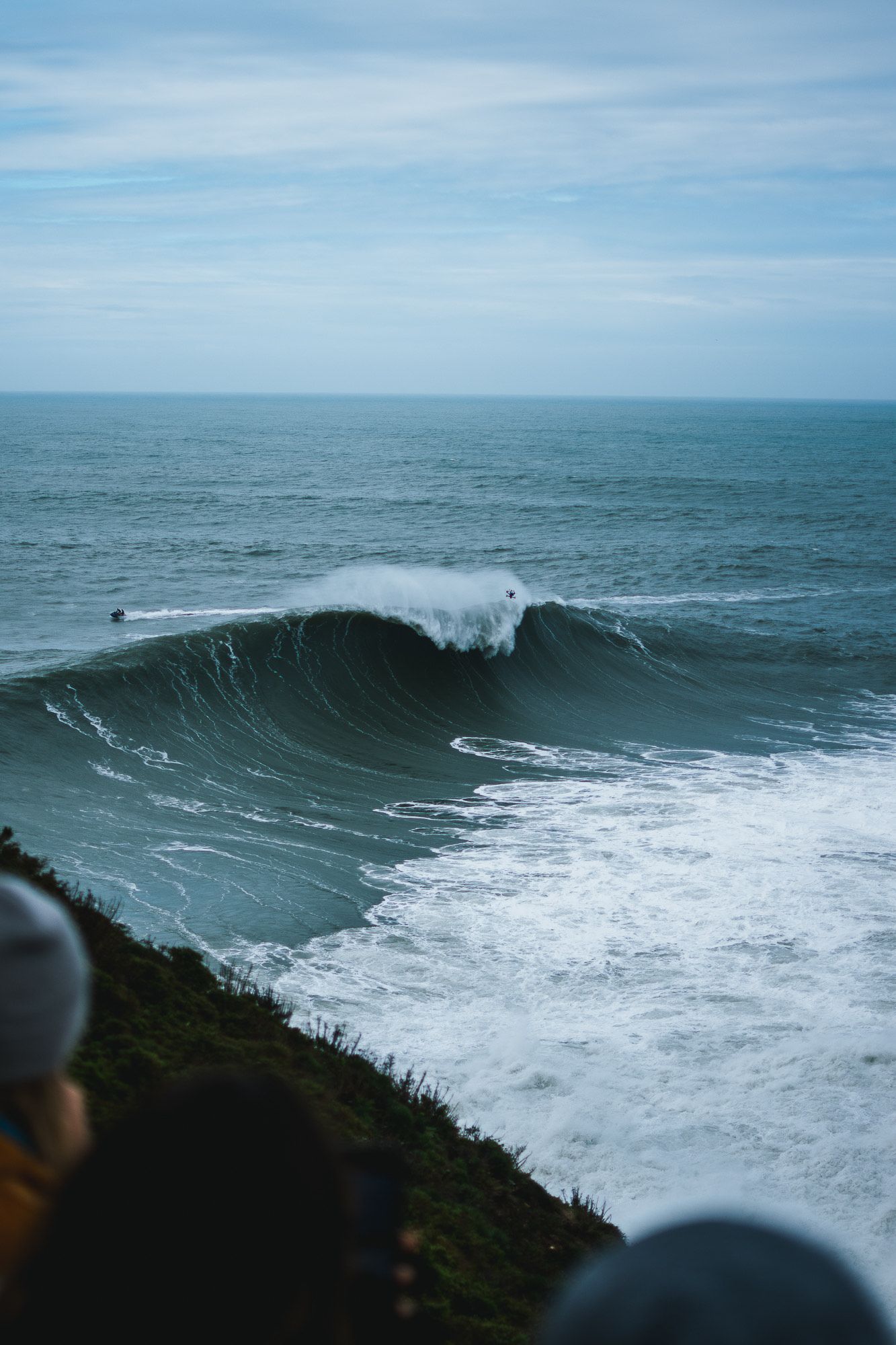 Large ocean wave cresting with white foam against blue sky.