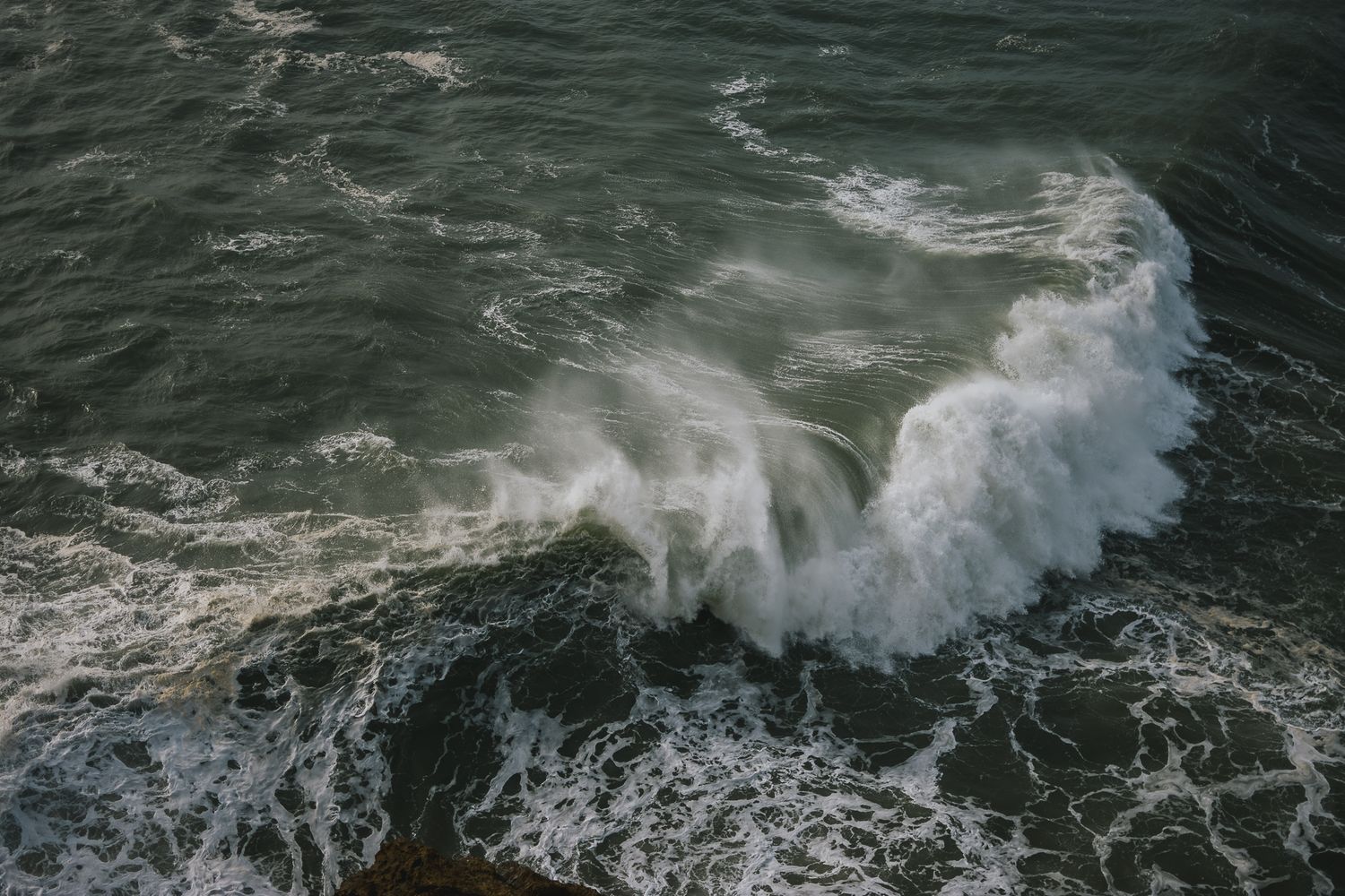 Dark ocean waves crashing and creating dramatic white spray patterns.