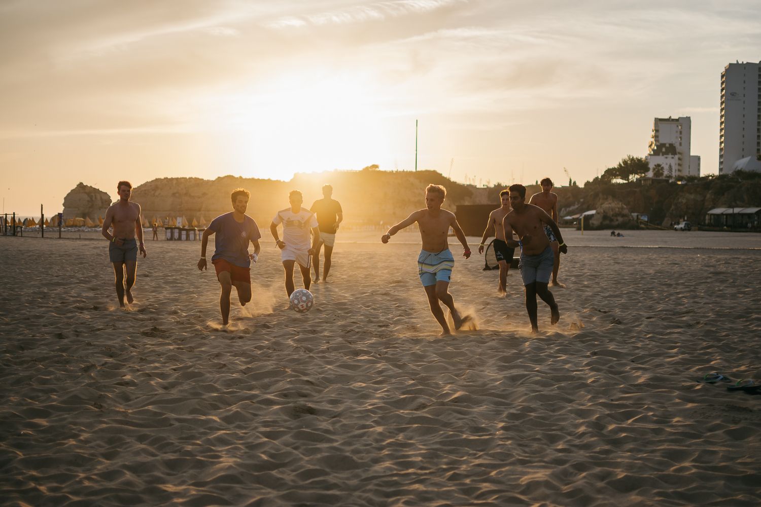 Silhouettes of people running on a beach during golden hour sunset.