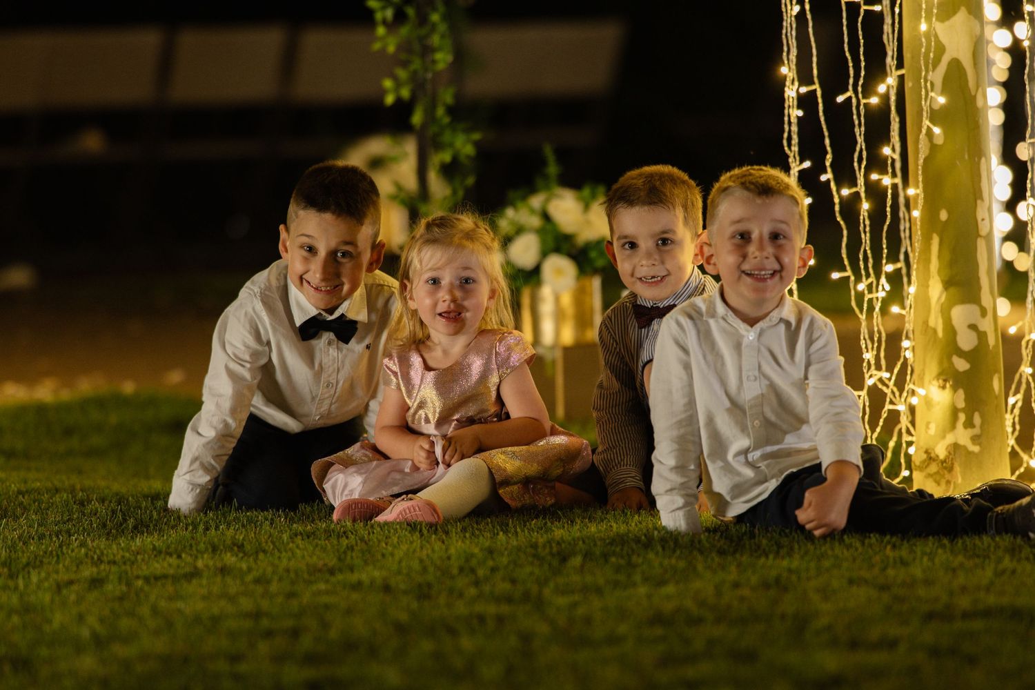 Children lying on grass near illuminated outdoor event setup.