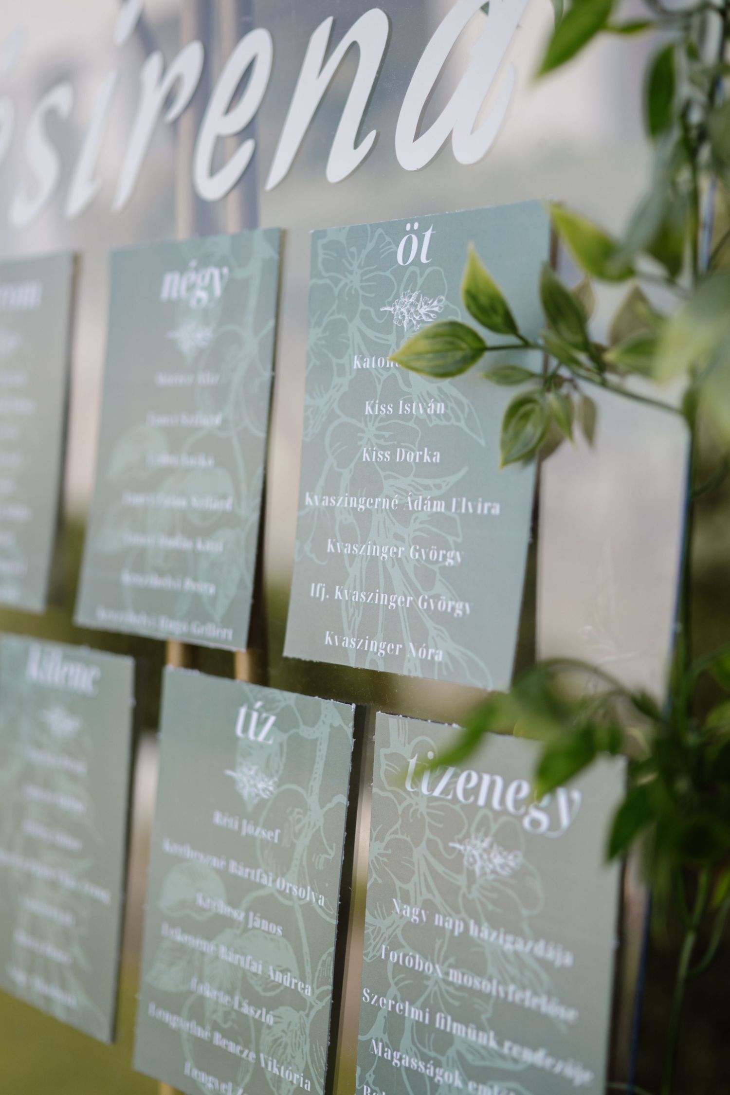 Wedding seating chart display with elegant calligraphy and greenery decorations.