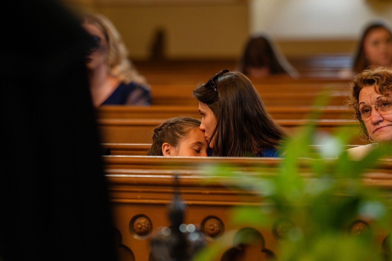 Wedding guests seated in wooden church pews during a ceremony.
