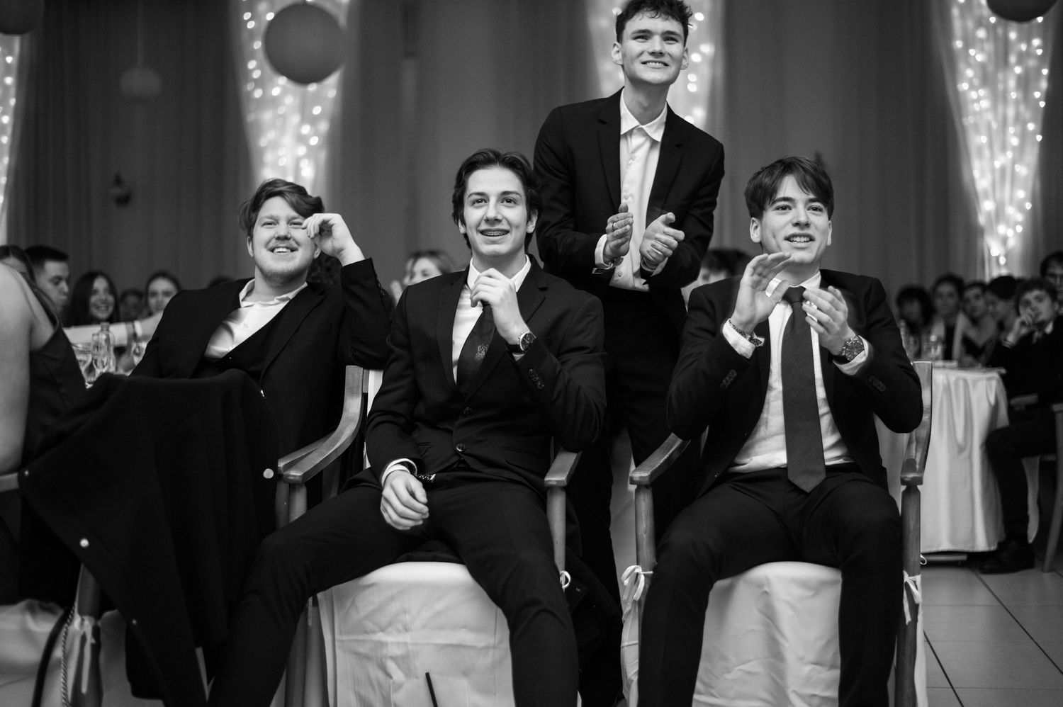 Black and white photo of wedding guests clapping and celebrating during reception festivities.