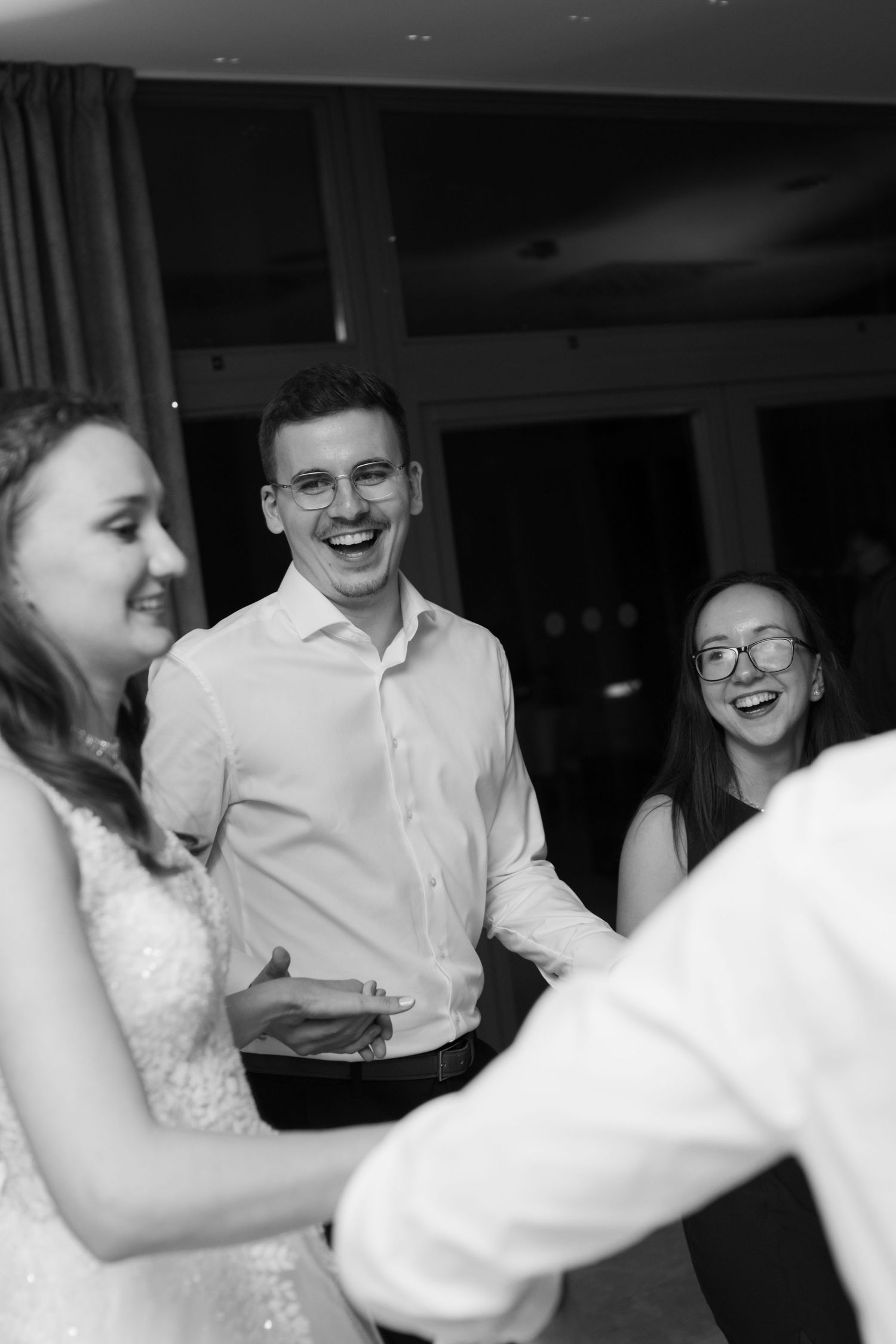 Wedding guests laugh and dance together during a reception celebration.