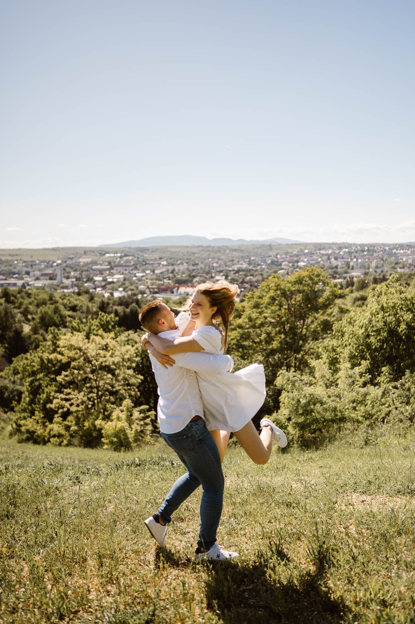 Romantic sequence showing a couple spinning and embracing on a hilltop overlooking a city.