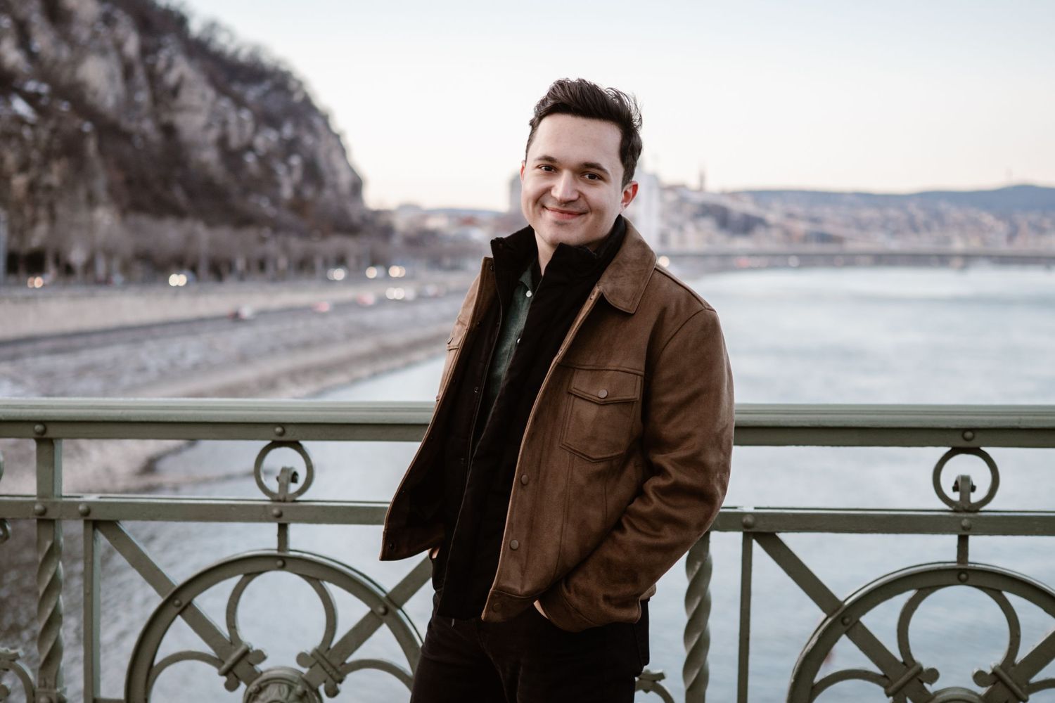 Casual outdoor photoshoot along waterfront railing with scenic coastal view.