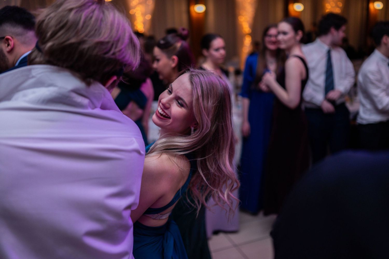 Energetic dance floor moments captured at an elegant wedding reception with ambient lighting.