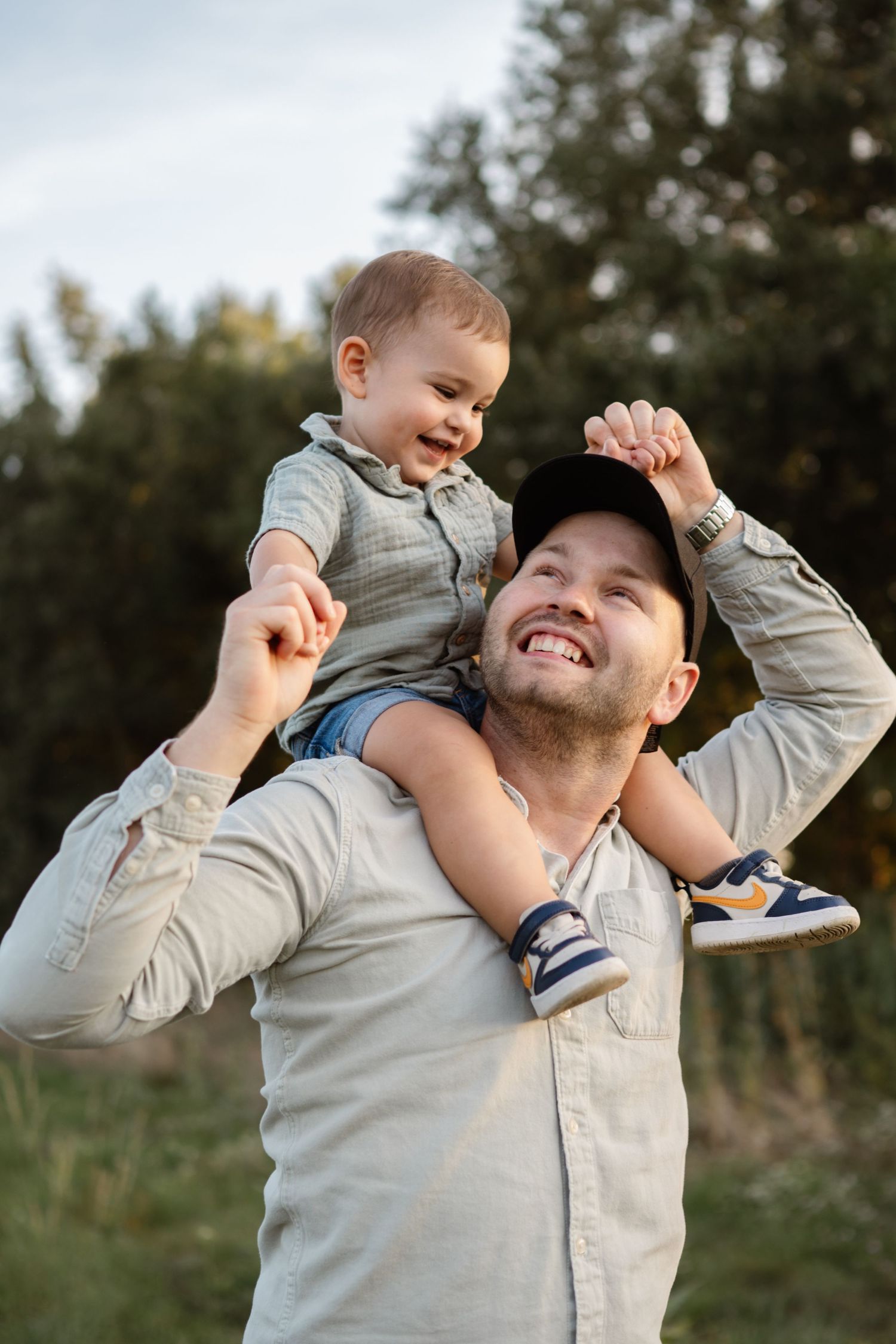 A joyful moment captured of a child riding on shoulders outdoors during golden hour.