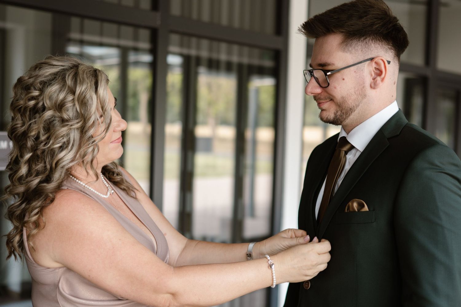 Wedding preparation moment as someone helps adjust formal attire.
