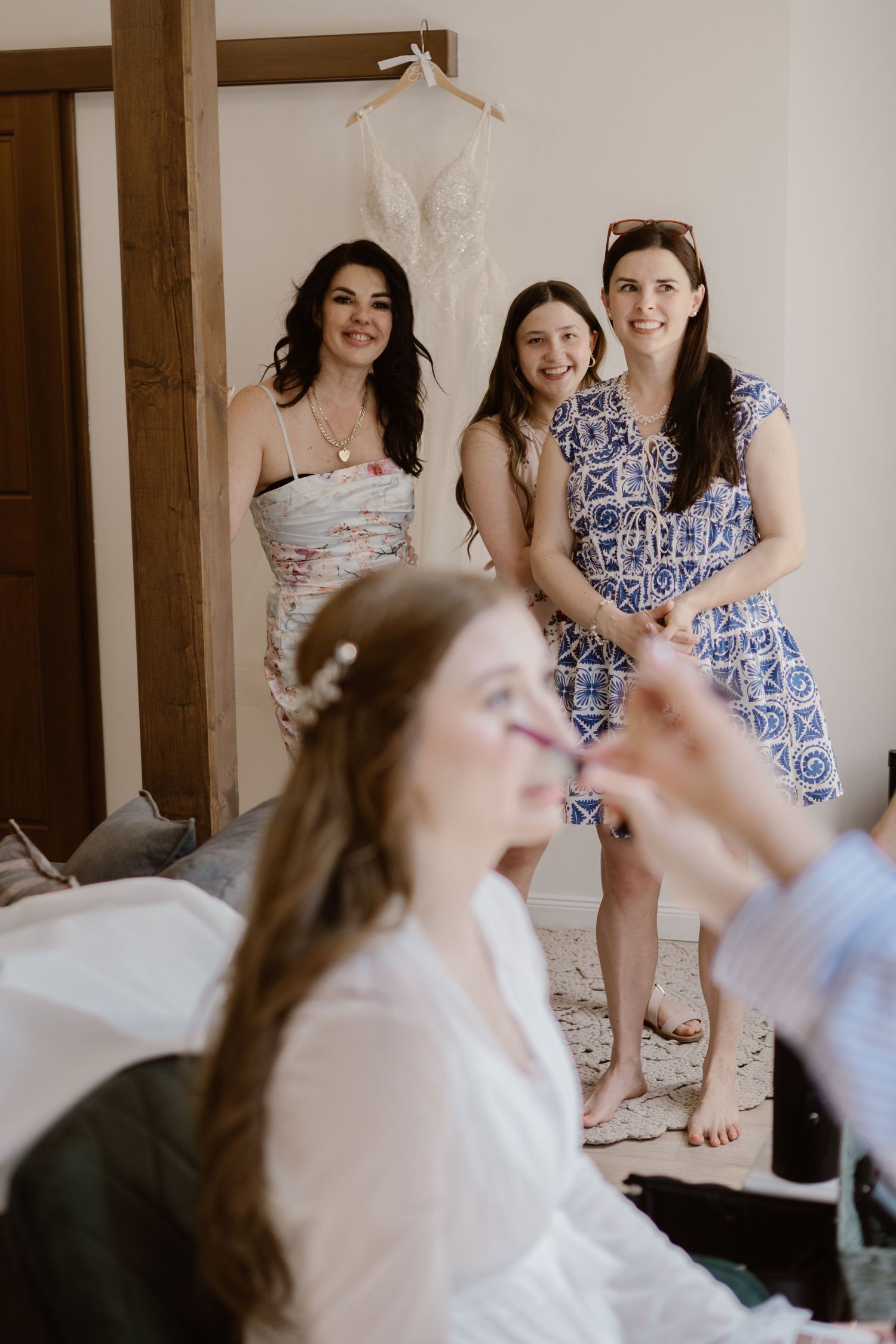 Wedding preparation scene with people in blue and white dresses in a bright room.