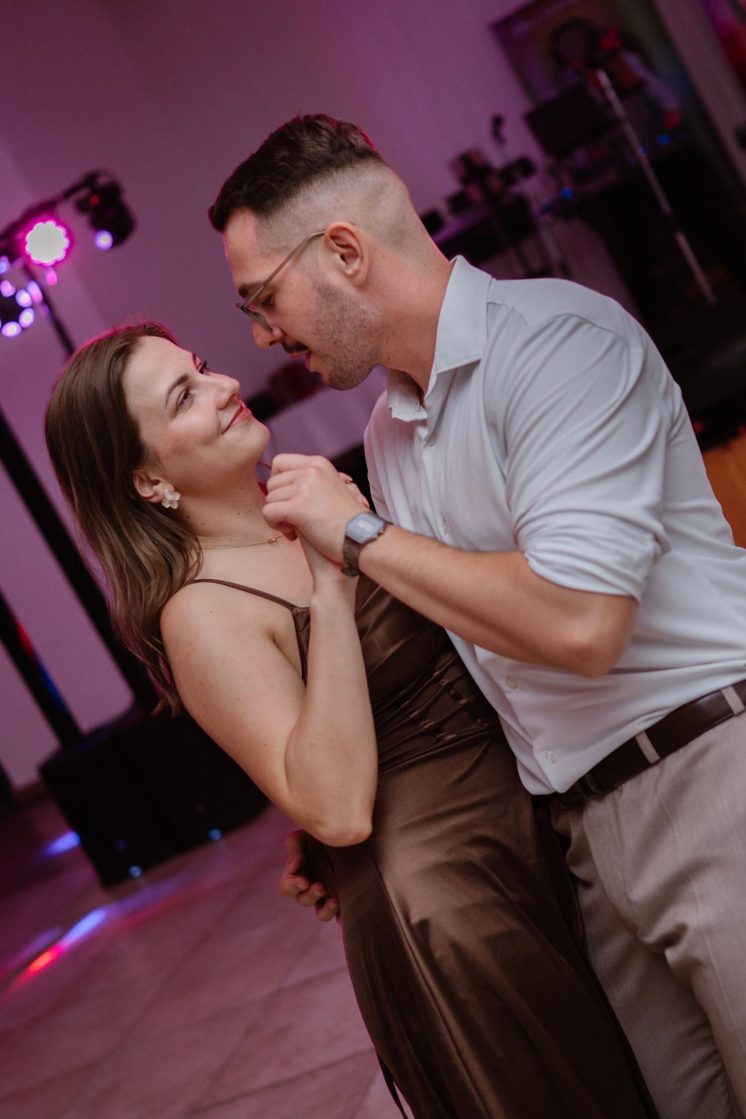 Couples sharing intimate dance moments under purple mood lighting.