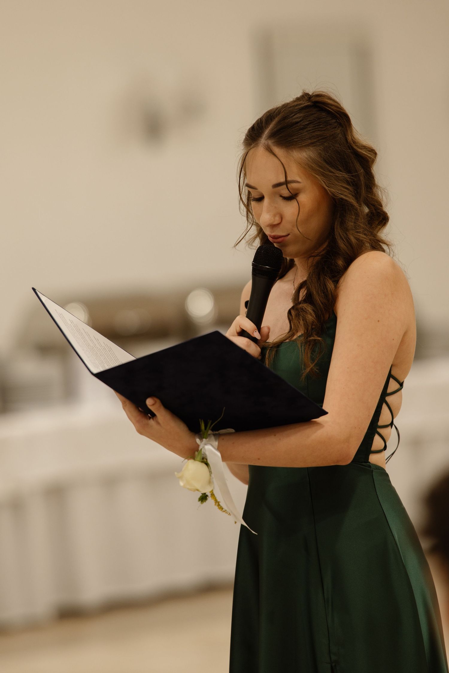 Person in dark formal dress reading from book during ceremony.