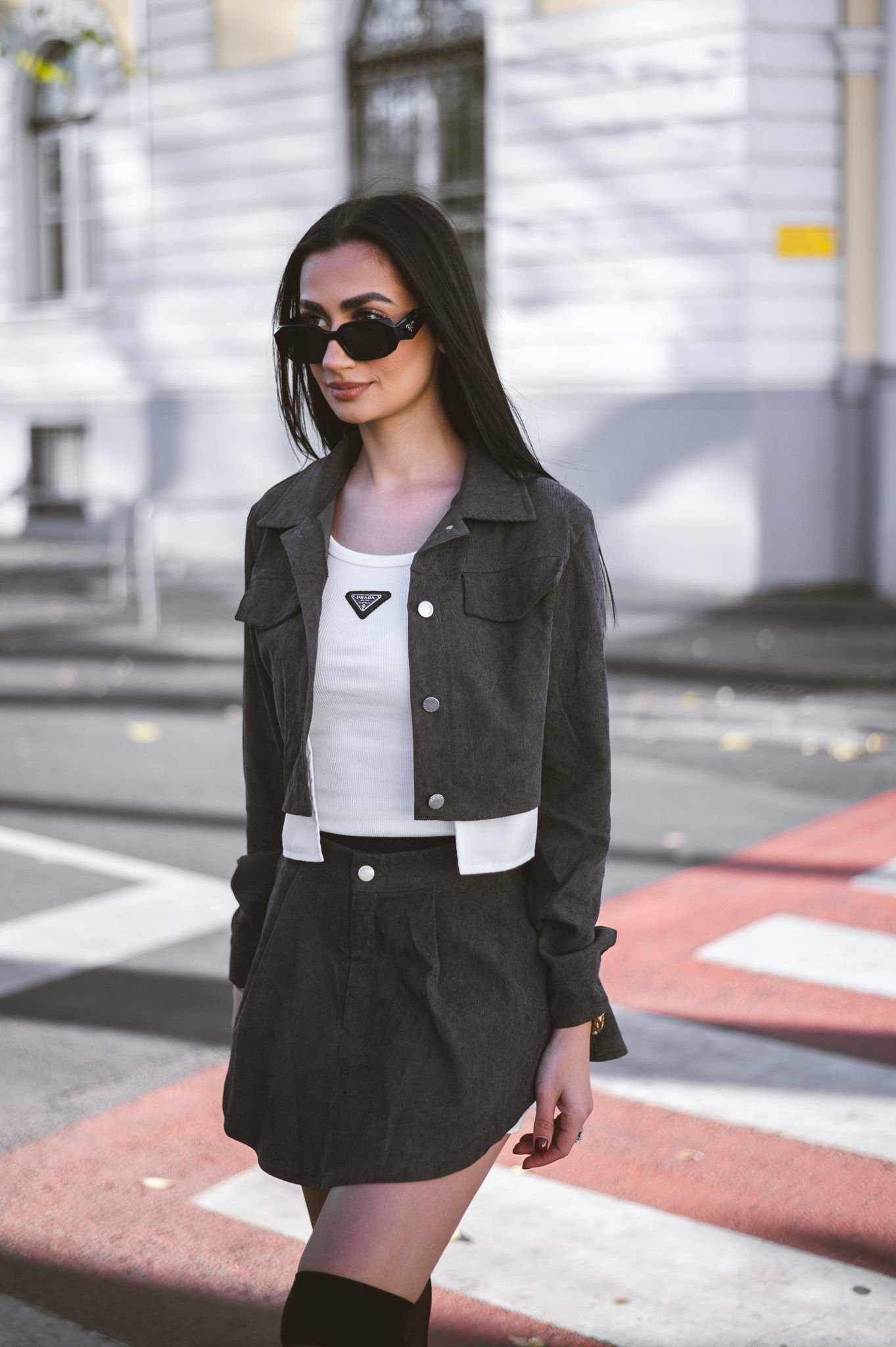 Stylish street fashion look featuring a black cropped jacket, white top and dark mini skirt.
