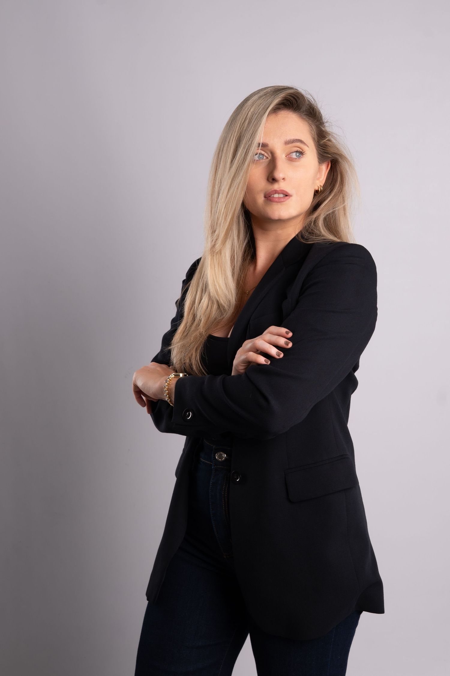 Fashion portrait series with model in black blazer striking dynamic poses against grey backdrop.