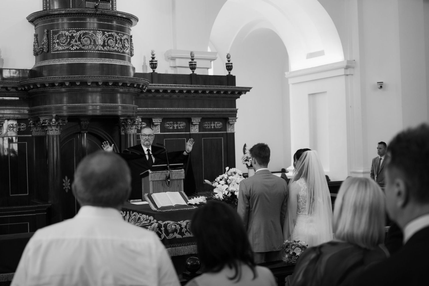 Officiant blessing couple during elegant church wedding ceremony in black and white photography.