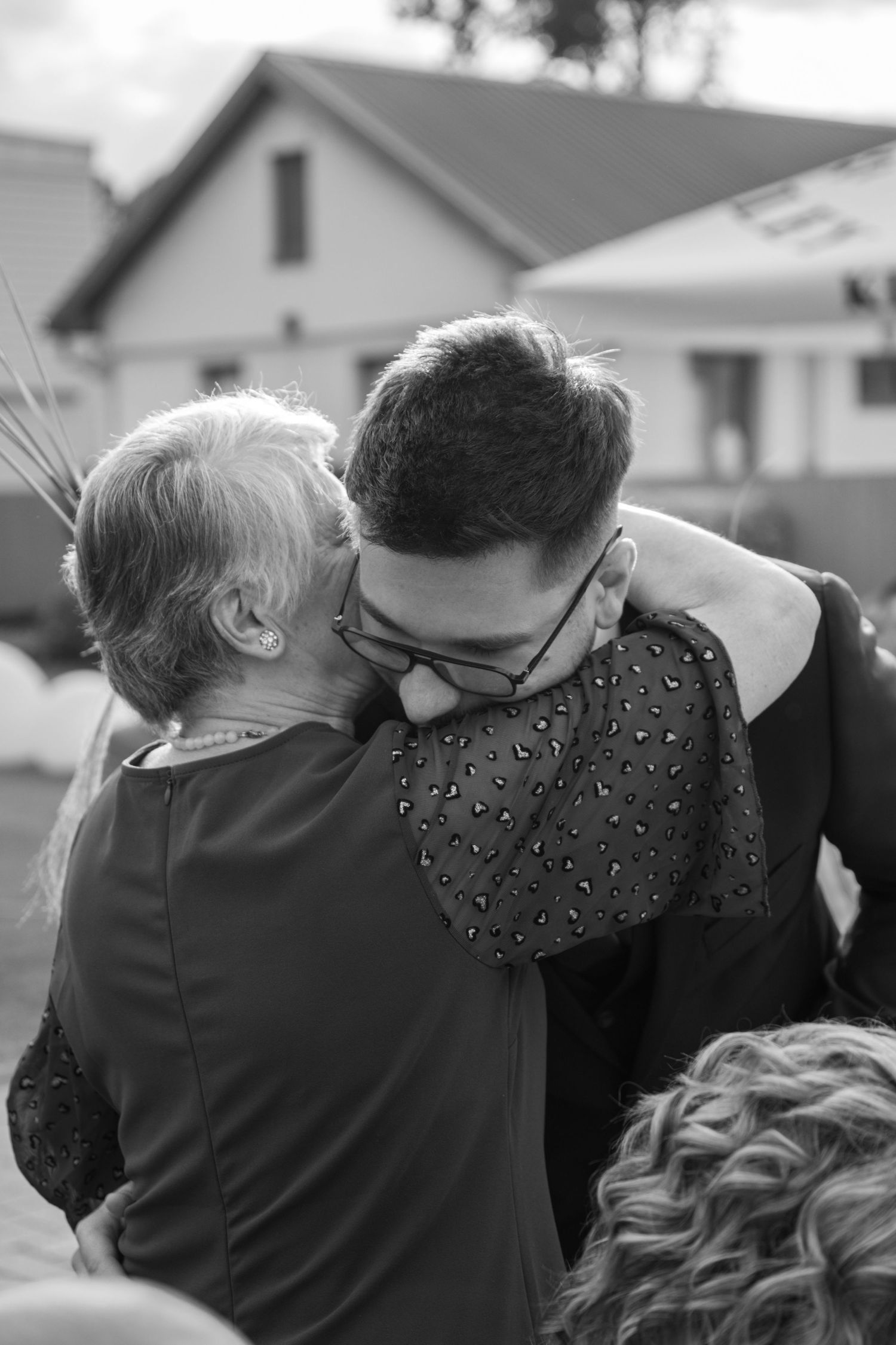 Black and white candid shots of emotional embraces at a wedding.
