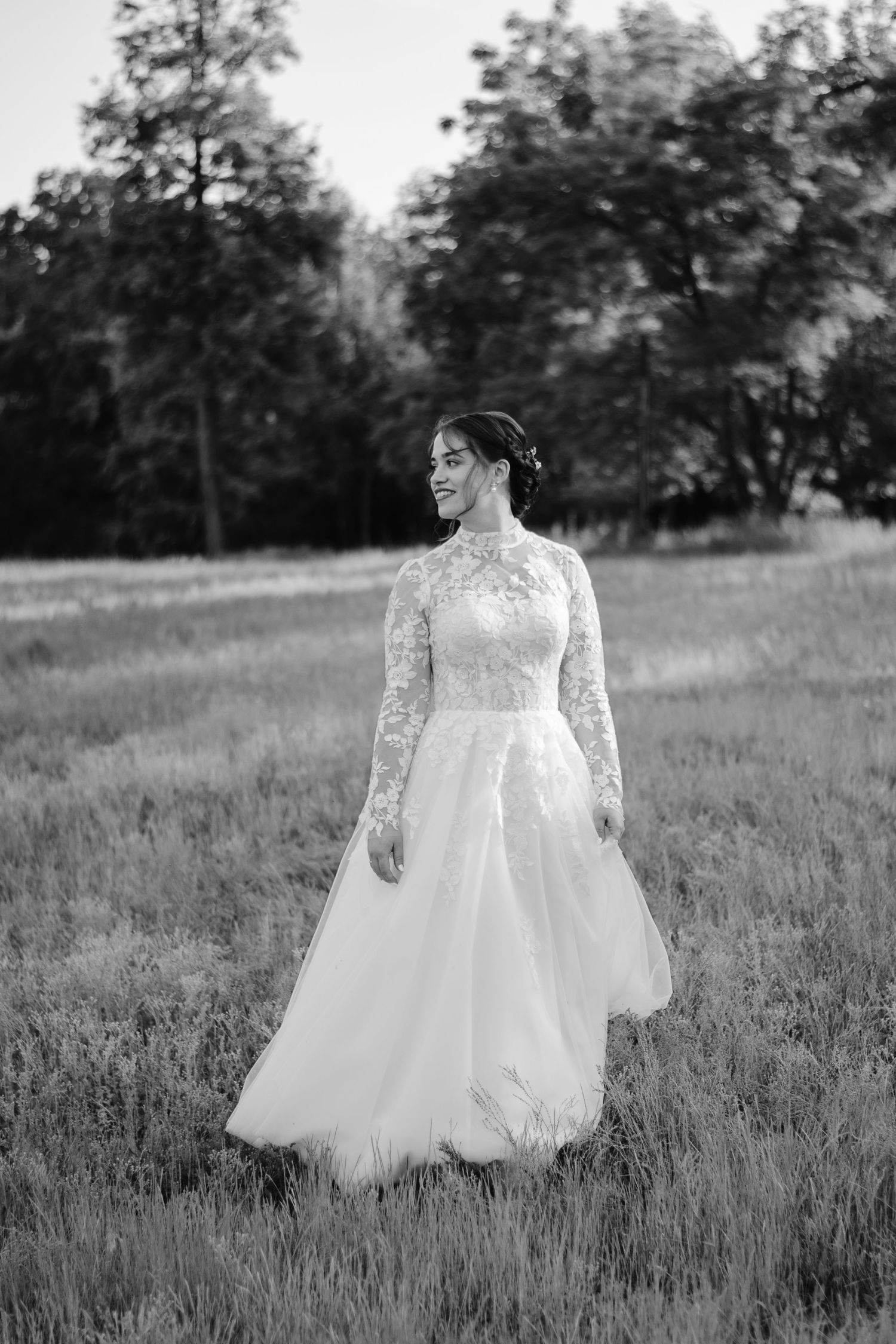 Black and white portraits of a bride in a lace wedding gown twirling in a meadow.