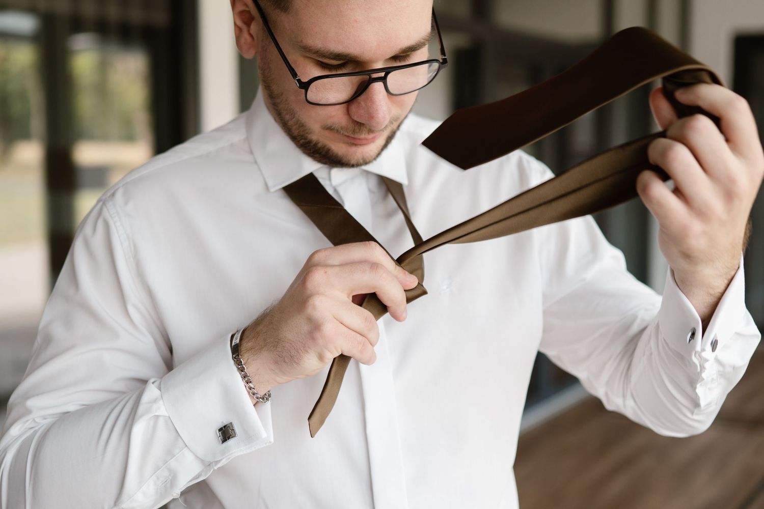 Groom adjusting his tie while getting ready for the wedding ceremony.