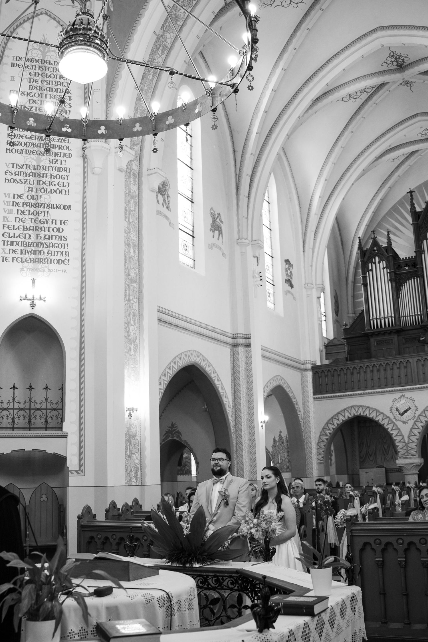 Black and white photo of a wedding ceremony in a grand cathedral with vaulted ceilings and organ pipes.